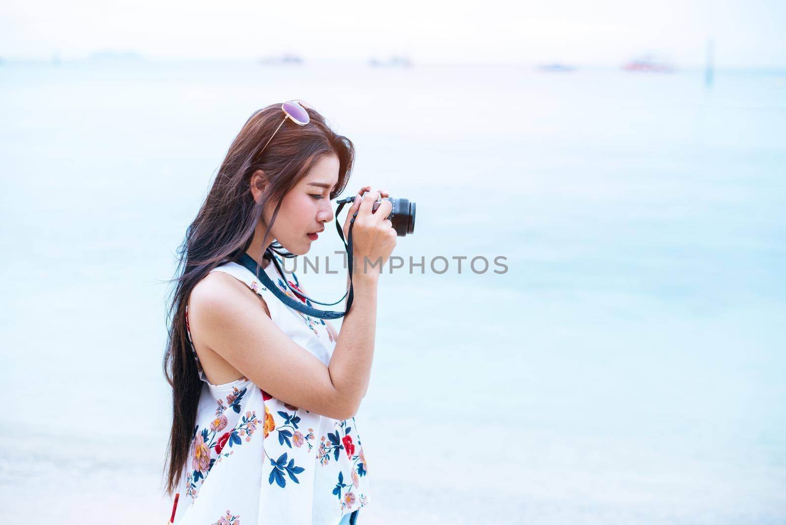 Asian woman enjoy take photo by digital camera at beach. Single and lonely woman concept. Happiness and Lifestyle concept. Beauty and Nature theme. Ocean and sea background. Technology and woman day