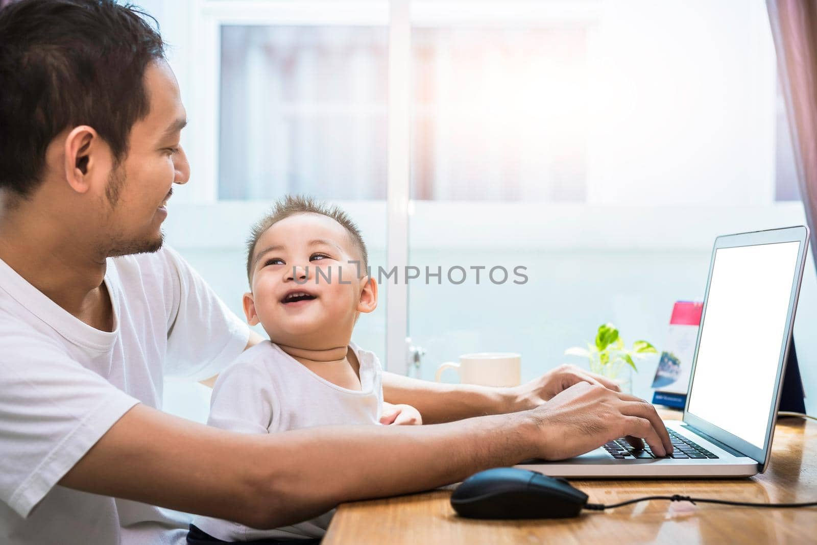 Single dad and son using laptop together happily. Technology and Lifestyles concept. Happy family and baby theme.