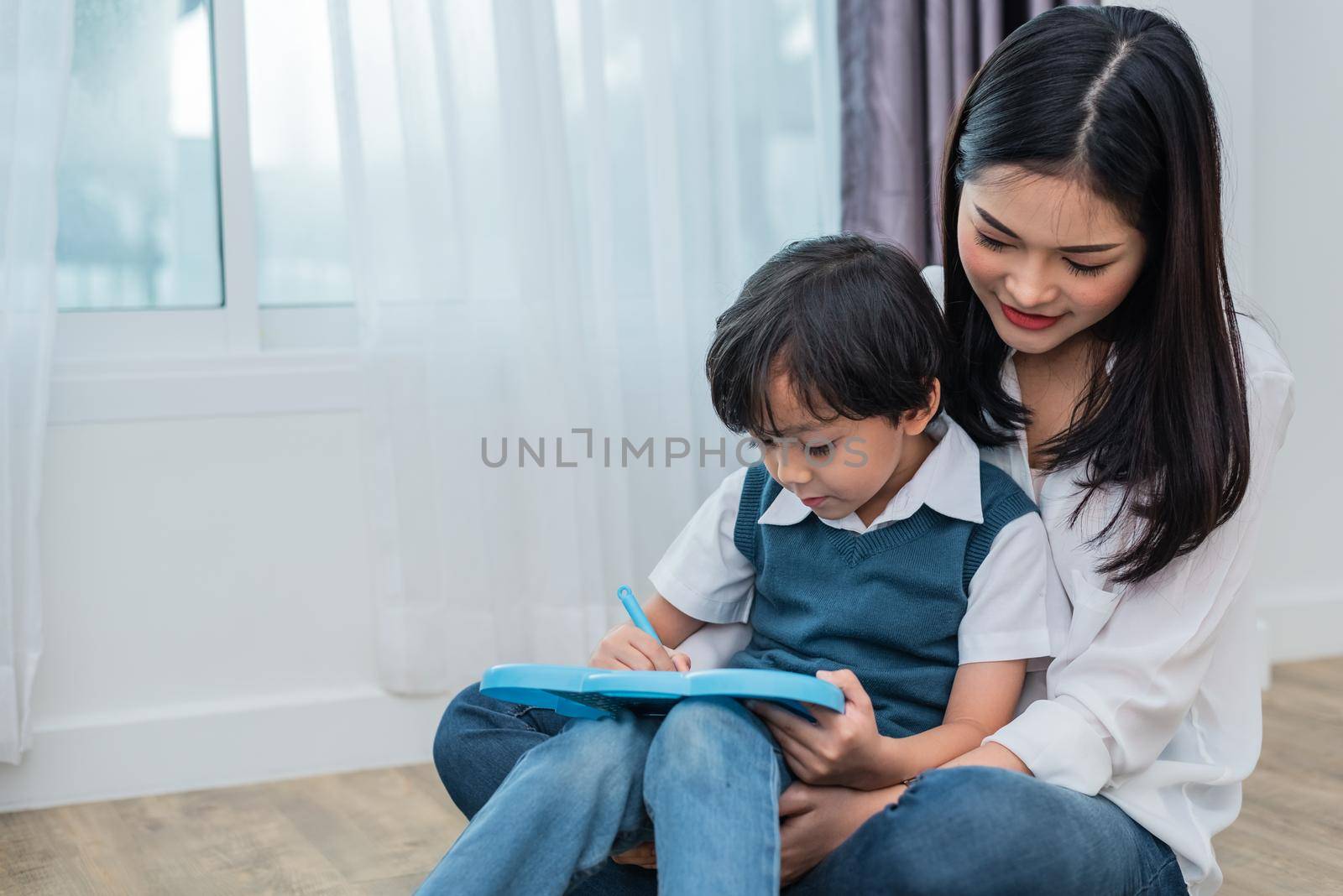 Asian mom teaching cute boy to drawing in chalkboard together. Back to school and Education concept. Family and Home sweet home theme. Preschool kids theme.