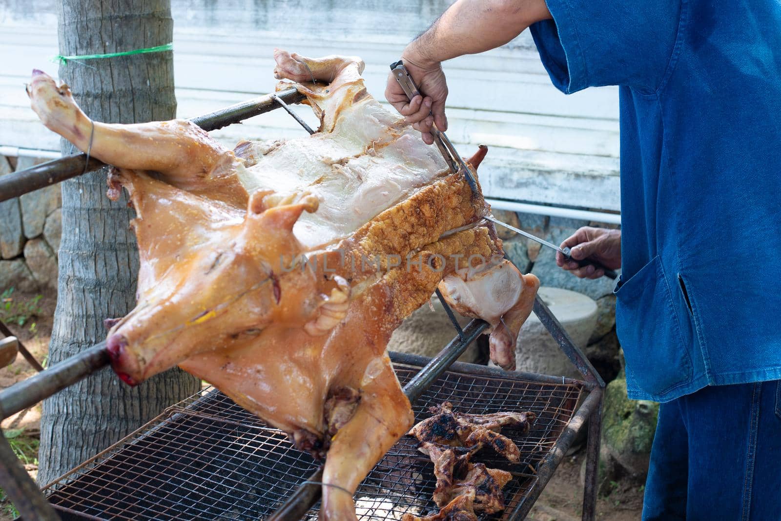 Man grilling grilled pork at street outdoor. Food and occupation concept. People and lifestyles theme.