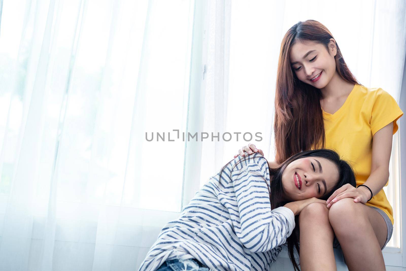 Asian couple take care together near white window with soft sunshine in happiness moment together. People and Lifestyles concept. Lesbian and friendships theme. LGBT theme.