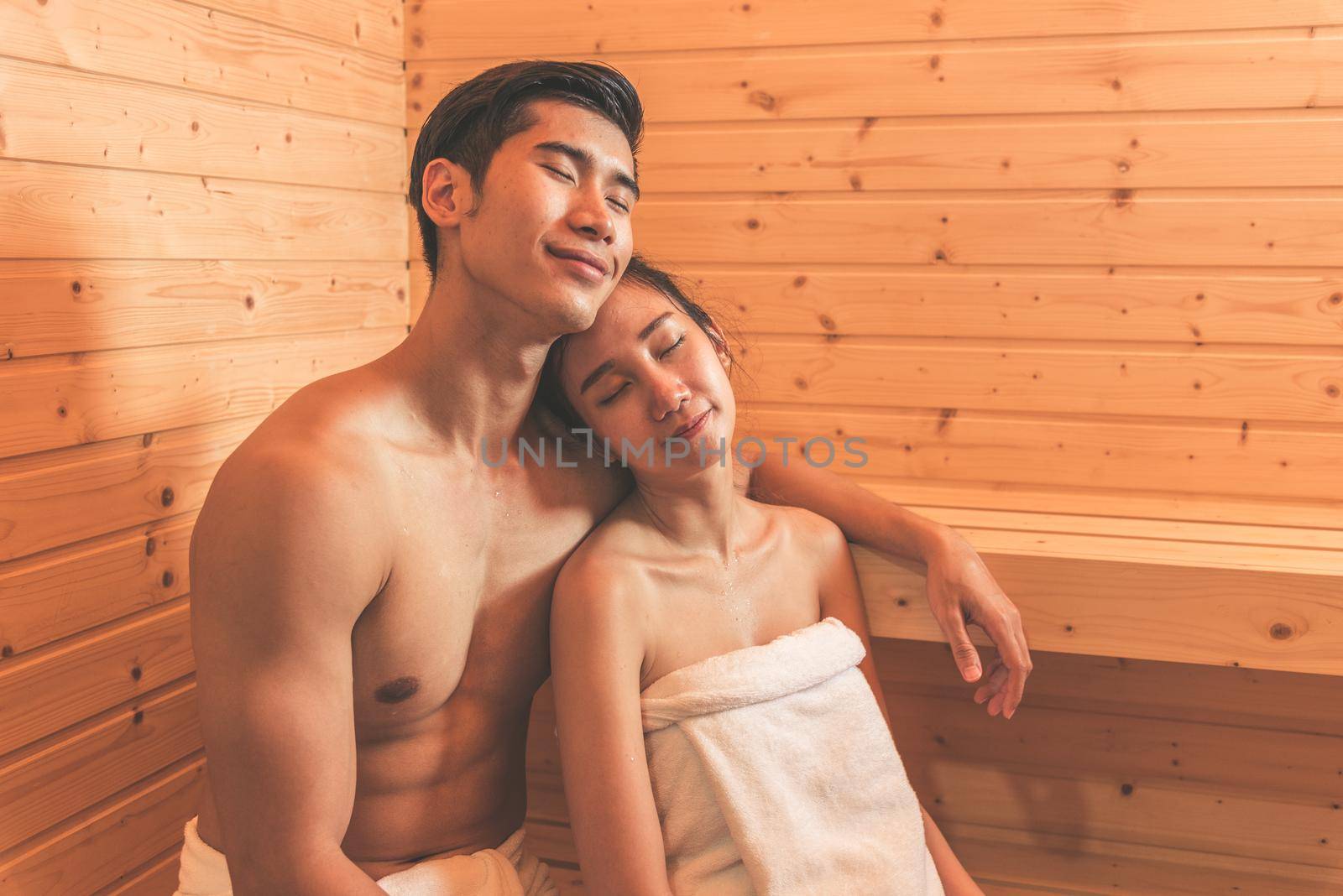 Young Asian couples or lovers have romantic relaxing in sauna room. Skin care heat treatment and body clean up and refreshing in spa with steam bath. Healthy and Honeymoon concept. Happiness together