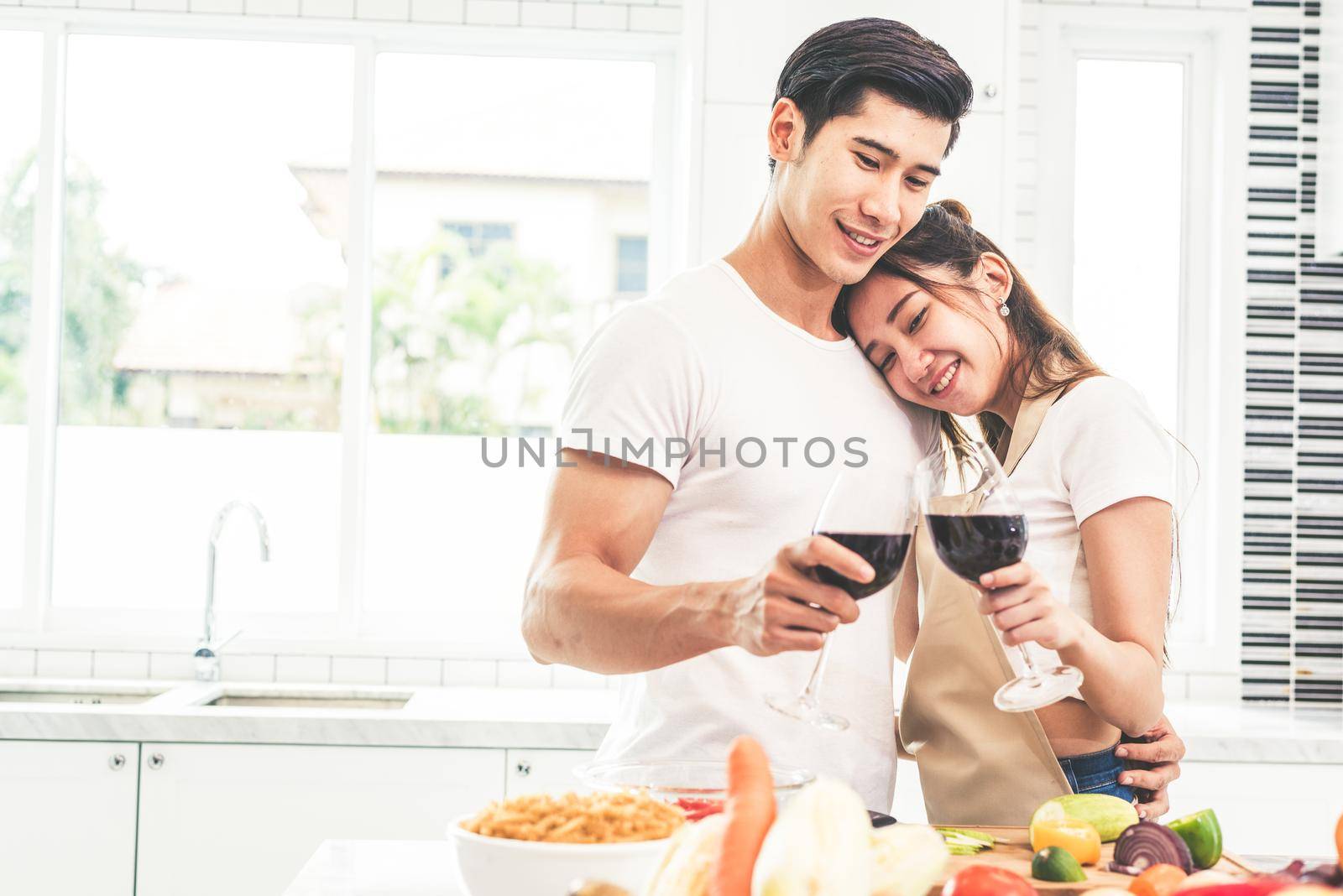 Asian lovers or couples drinking wine in kitchen room at home. Love and happiness concept Sweet honeymoon and Valentine day theme