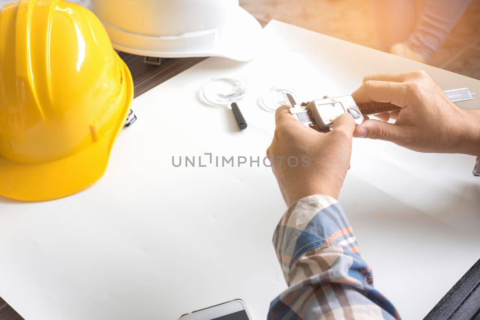 Construction engineer measuring with vernier caliper. Business and Technology concept. Safety helmet and Drawing paper elements. Civil and Drawing sketch theme.