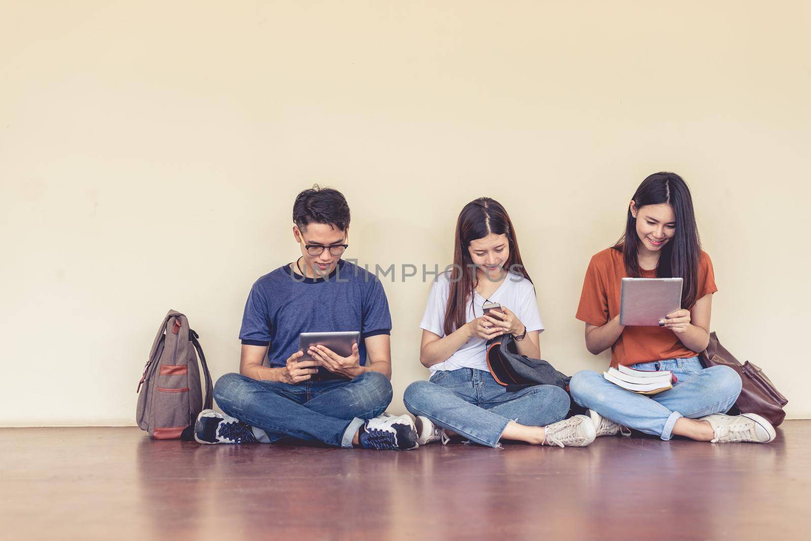 Group of Asian college student using tablet and mobile phone outside classroom. Happiness and Education learning concept. Back to school concept. Teen and people theme. Outdoors and Technology theme.