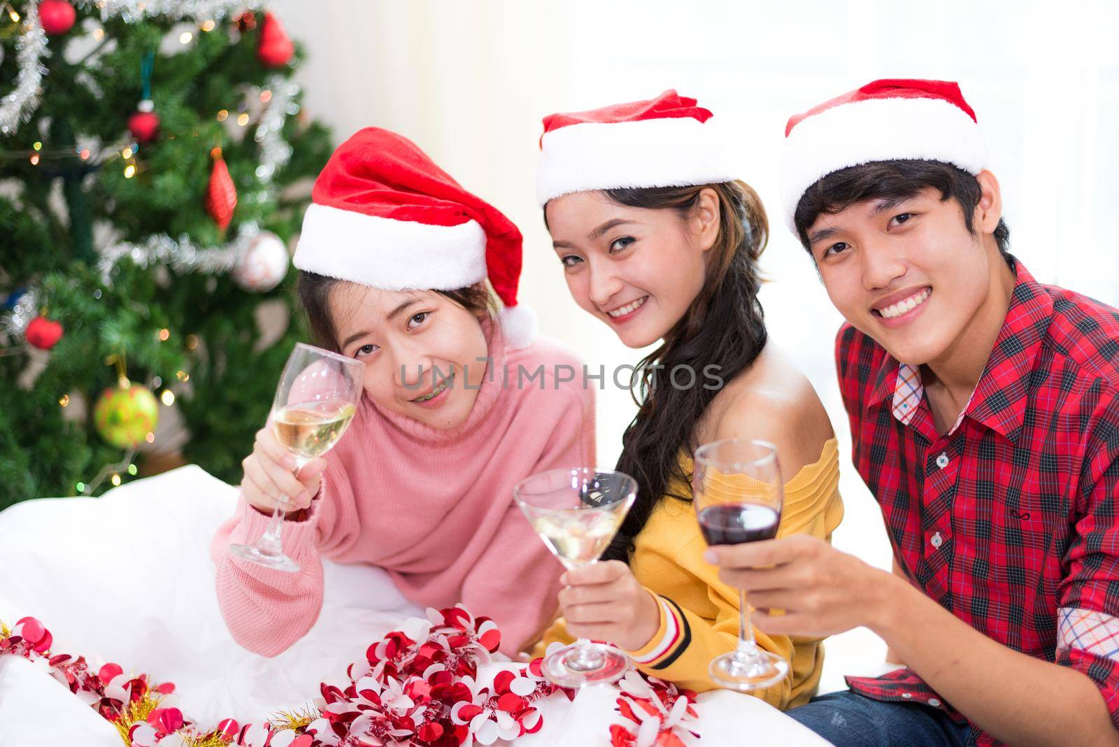 Group of young Asian people celebrating New year party in home with wine drinking glasses. New year and Christmas party concept. Happiness and Friendship concept. Relation and Funny together theme.
