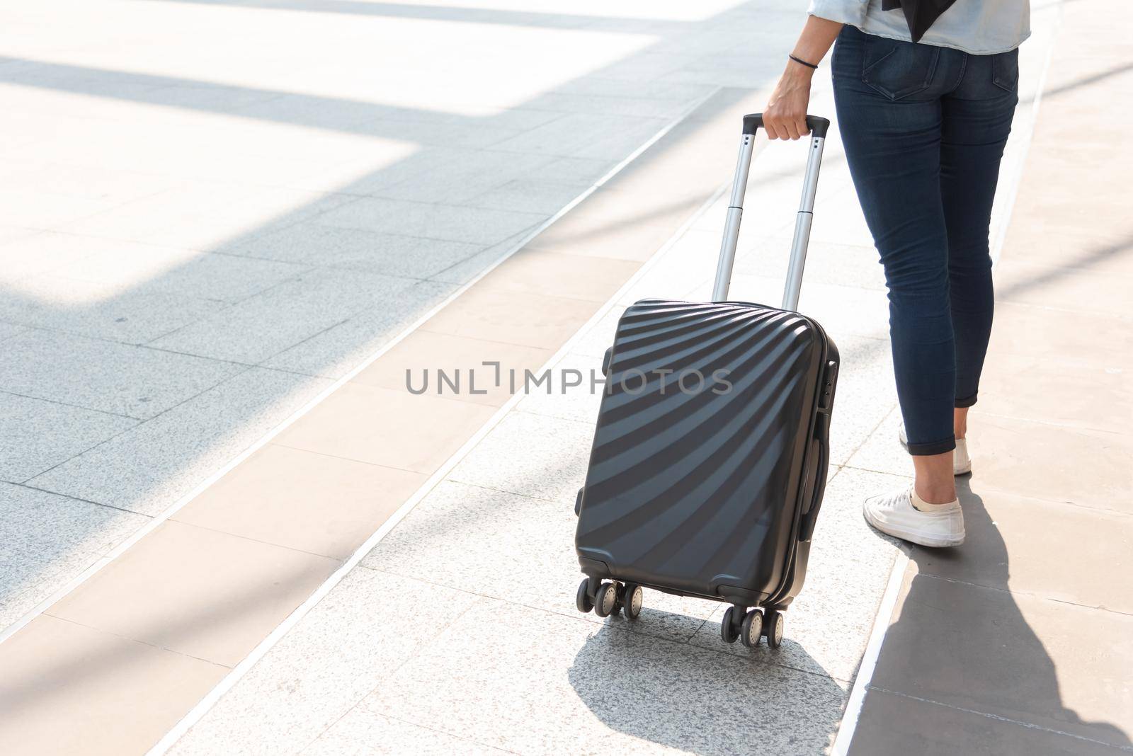 Close up woman and suitcase trolley luggage in airport. People and lifestyles concept. Travel and Business trip theme. Woman wear jeans going on tour and traveling around the world by alone solo girl