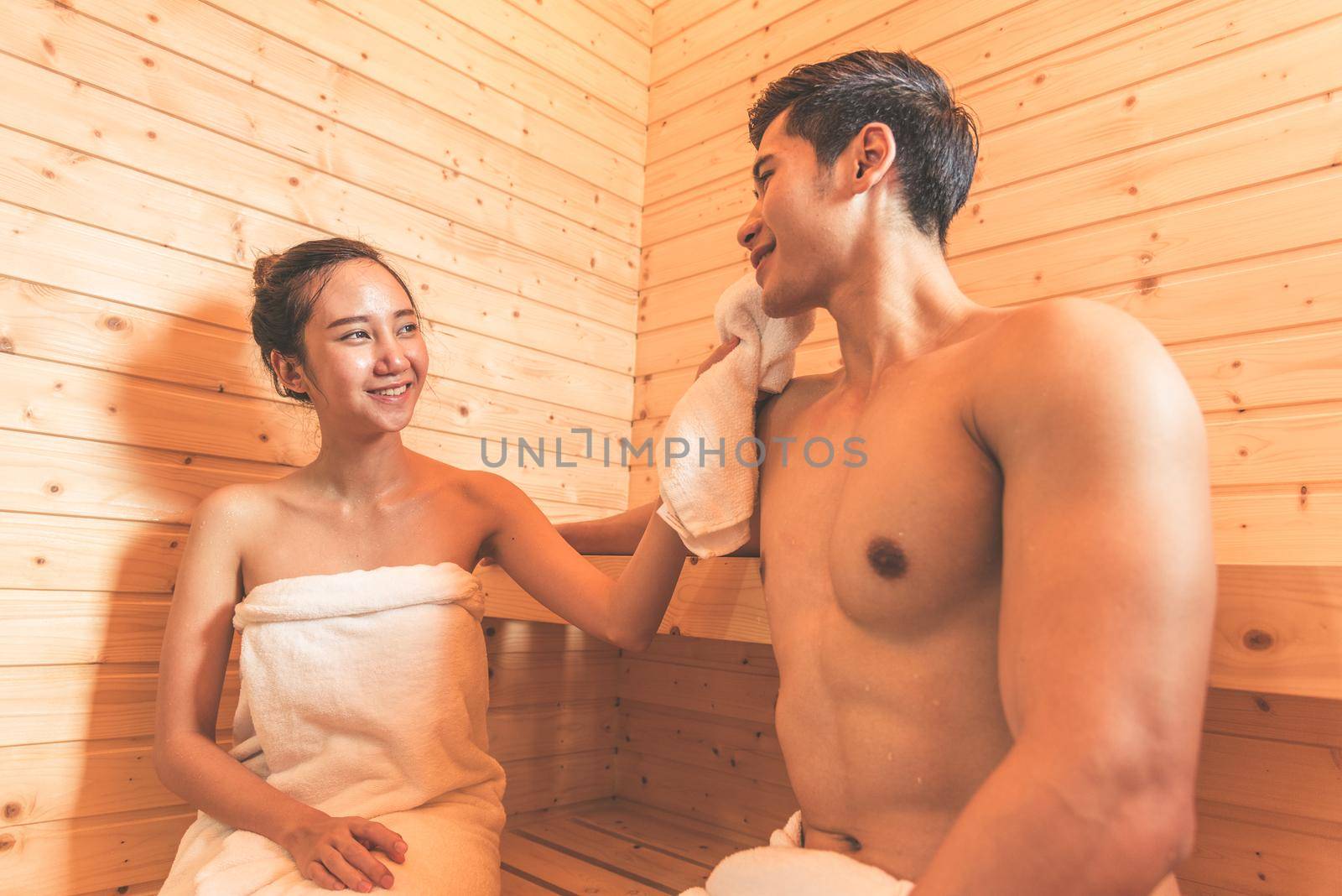 Young Asian couples or lovers have romantic relaxing in sauna room. Skin care heat treatment and body clean up and refreshing in spa with steam bath. Healthy and Honeymoon concept. Happiness together