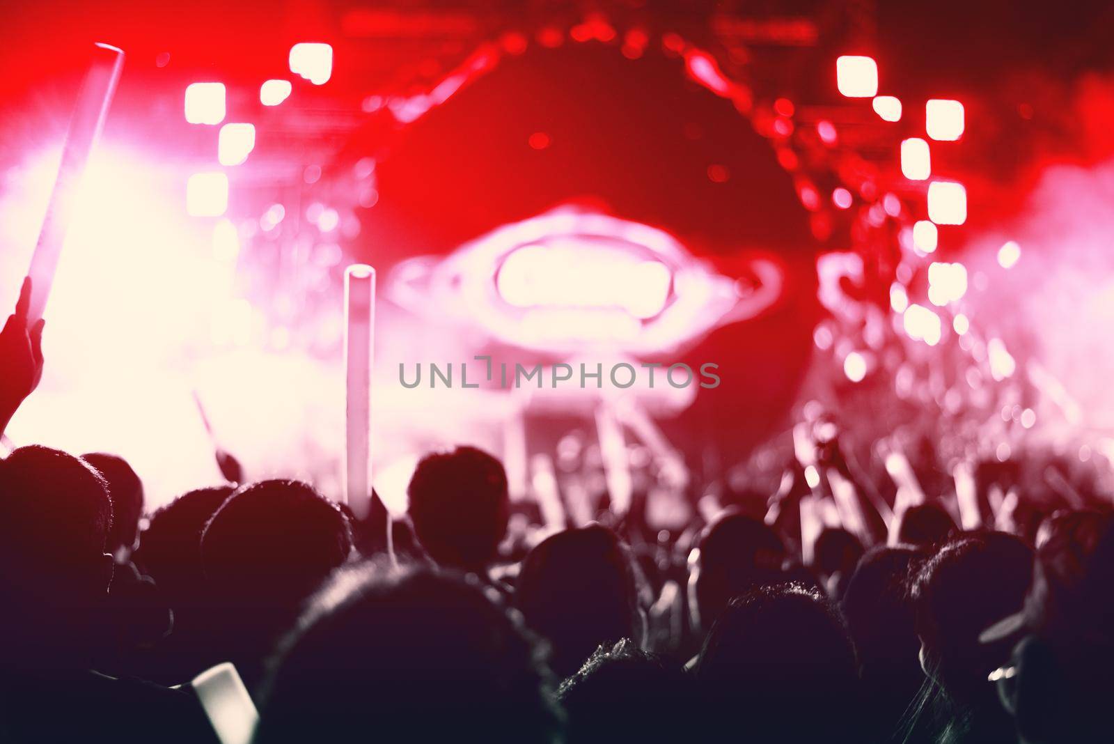 Rock concert with silhouettes people in happy gesture and raising up hands for cheer up singer. Entertainment and People concept. Singer and Audience theme. Red tone