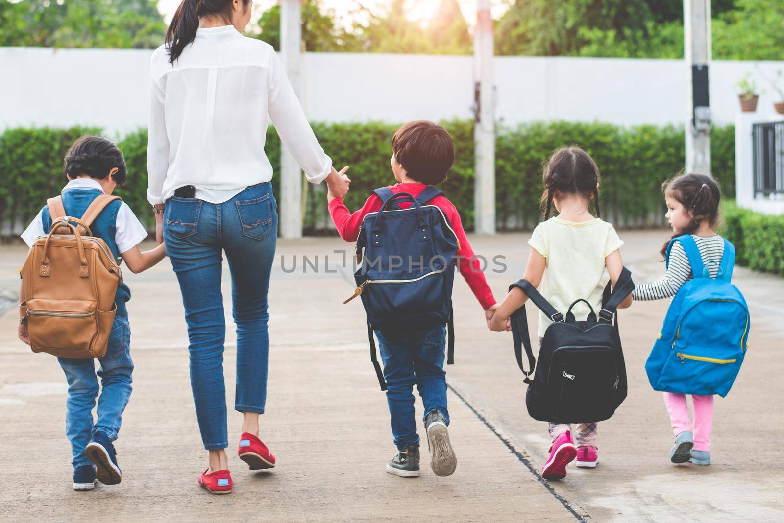 Back to school students mother group going school together. Parent send little boy and girl for first class semester term with schoolbag or satchel together. Collaborative learning and empathy daycare