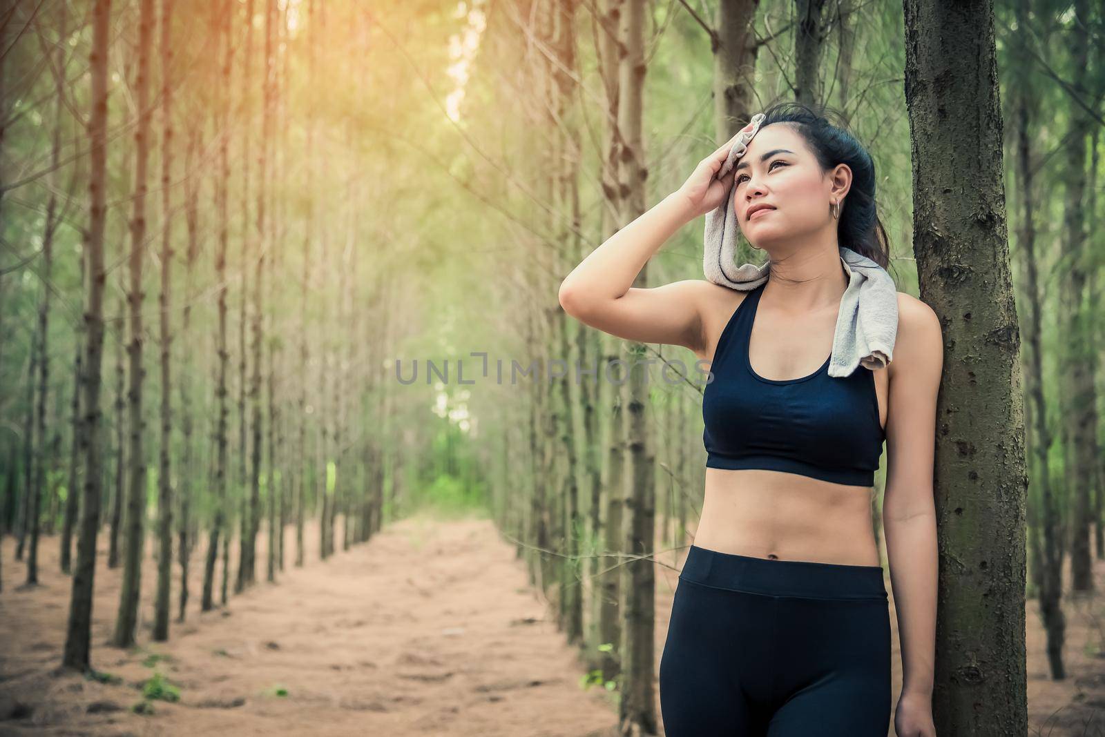 Asian beauty woman wiping the sweat in forest. Towel and sweat elements. Sport and Healthy concept. Jogging and Running concept. Relax and take a break theme. Outdoors activity theme.