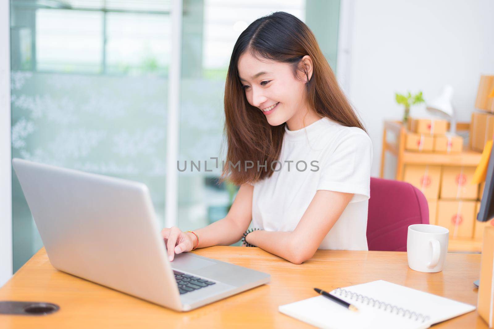 Asian woman enjoy herself while using laptops and internet in office. Business and marketing and part time concept. On line shopping and business success theme. Happy mood doing working job.