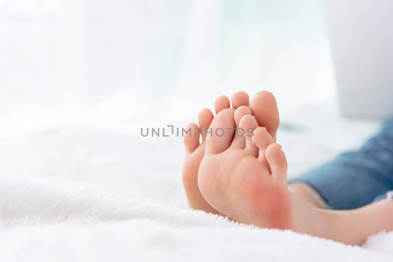 Closeup woman feet skin wearing jeans on white bed. Healthcare and health medical concept. by MiniStocker