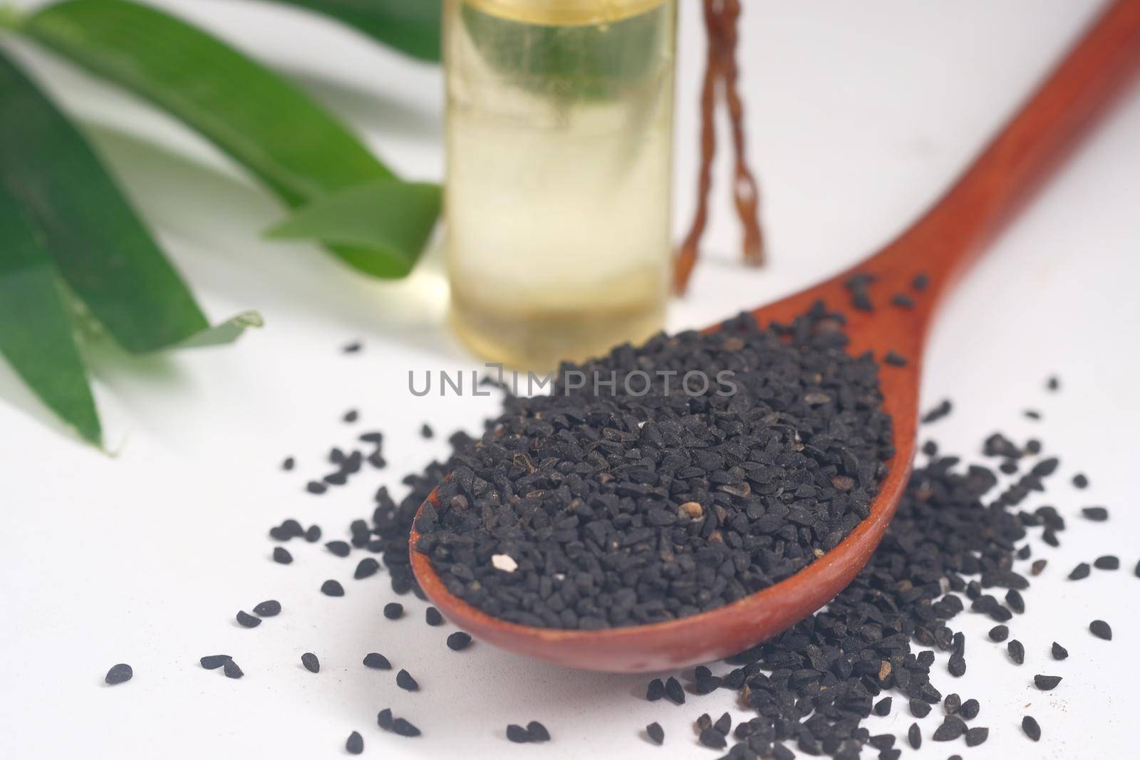 Black Cumin on spoon with oil in a jar on table