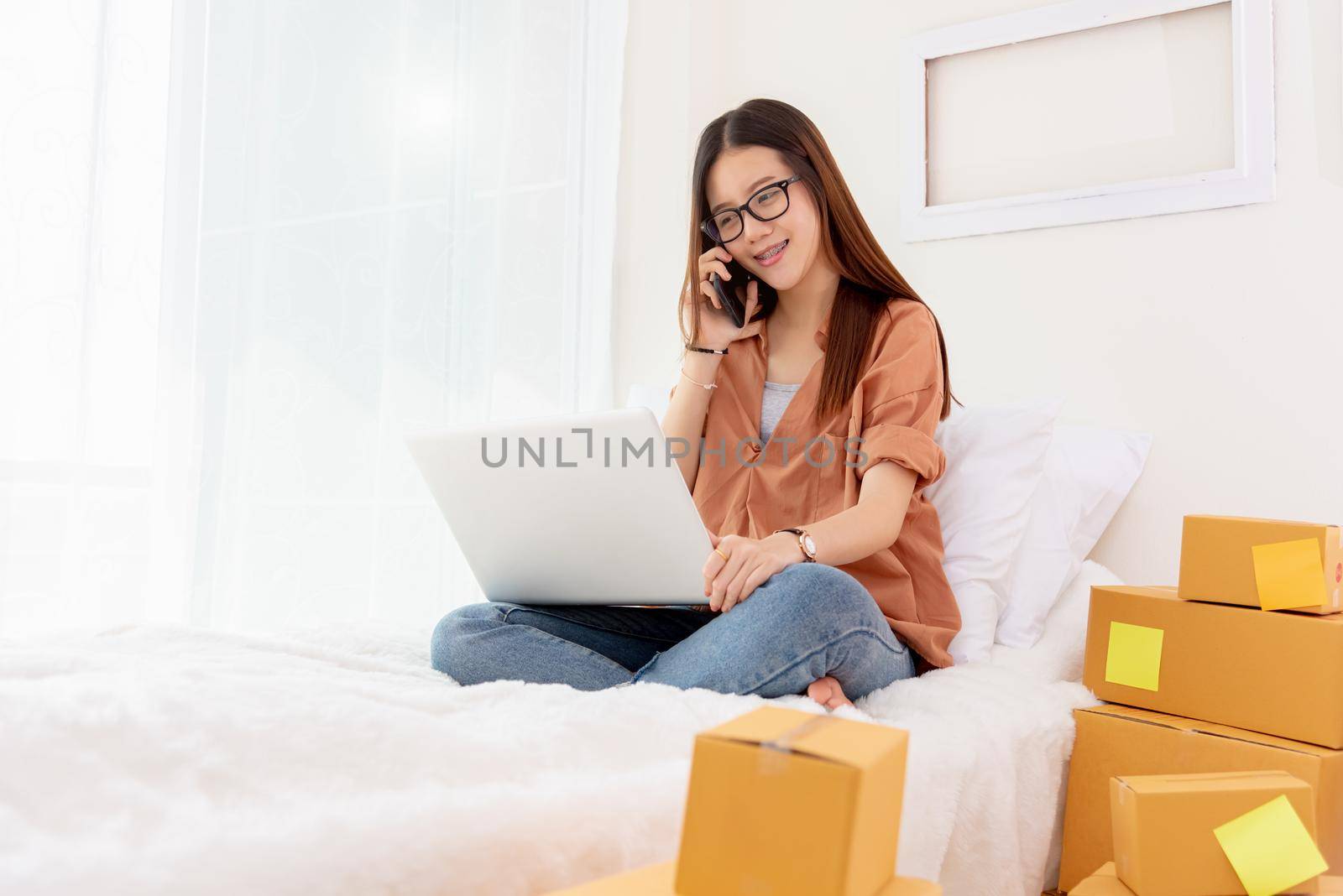 Beauty Asian woman using laptop and calling phone on bed. Business and Technology concept. Delivery and Online shopping concept. Post and Service theme. People lifestyle remote work in domestic house