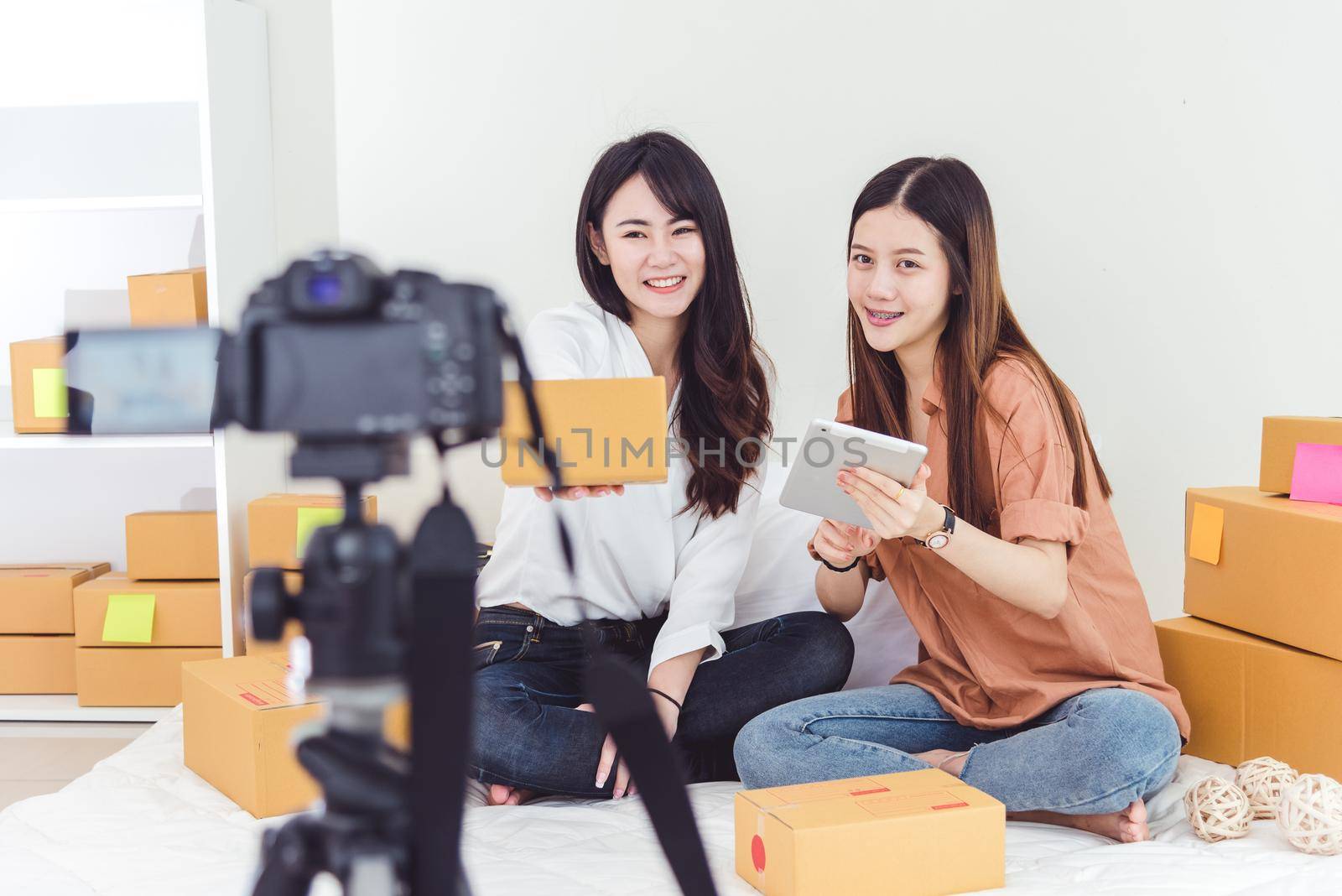 Two Asian women using digital video camera for recording and presenting new product advertisement. Vlog and influencer concept. People part time job and occupation. Young teenagers using technology by MiniStocker