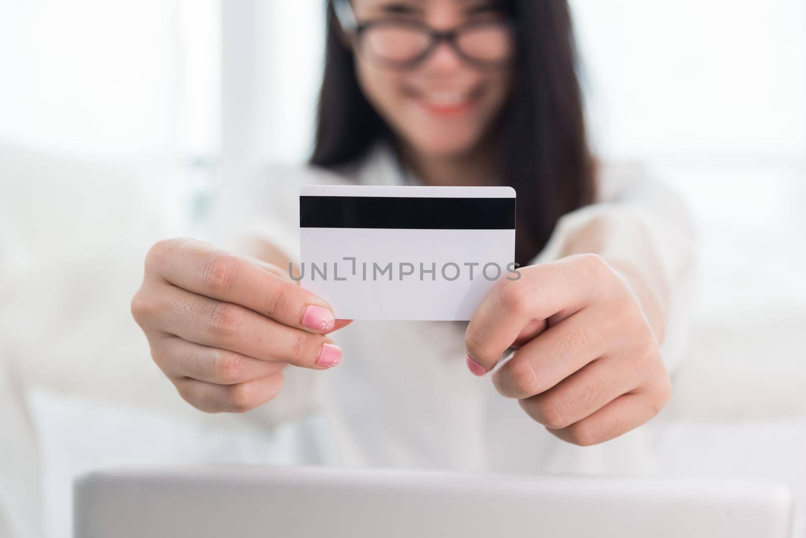 Young Asian woman use credit card for online shopping with laptop. Business and Banking payment concept. Price sale and promotion concept. Technology and Computer theme. E-commerce and Marketing theme