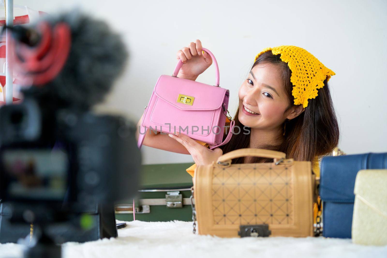 Beauty Asian Vlogger blogger selling woman bag online with professional DSLR digital camera film video live. Woman coaching trading and review clothing product. Business presentation training class