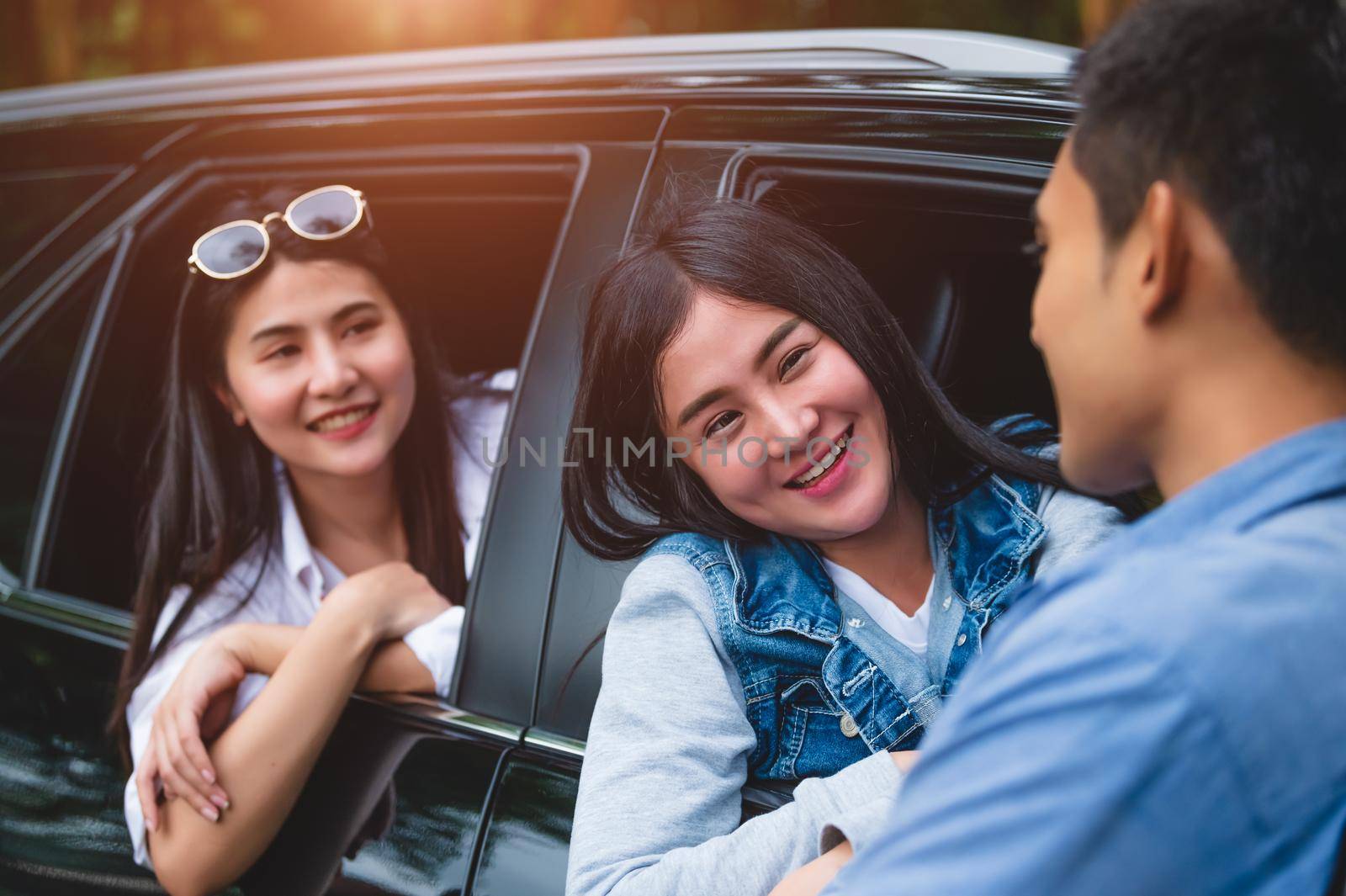 Asian women in car flirted by man during travel in forest. Boy talking to girls for meeting. People lifestyles and weekend tour concept. Summer and nature theme. Mountain camping people group holiday