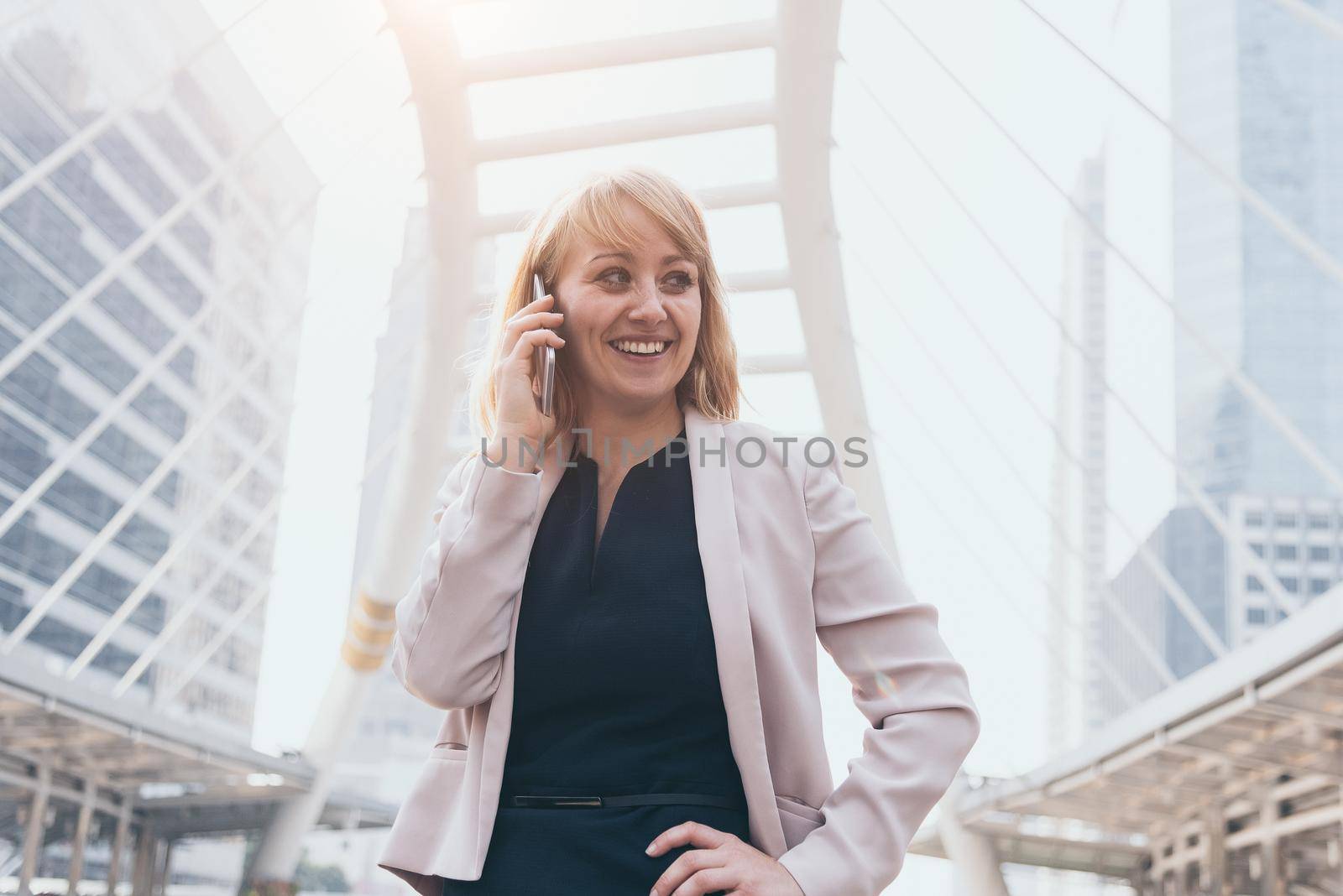 Happy businesswoman using smart phone to communicate and talk to business agreement in urban city background. People lifestyles and technology concept. Outdoor working and social distancing concept