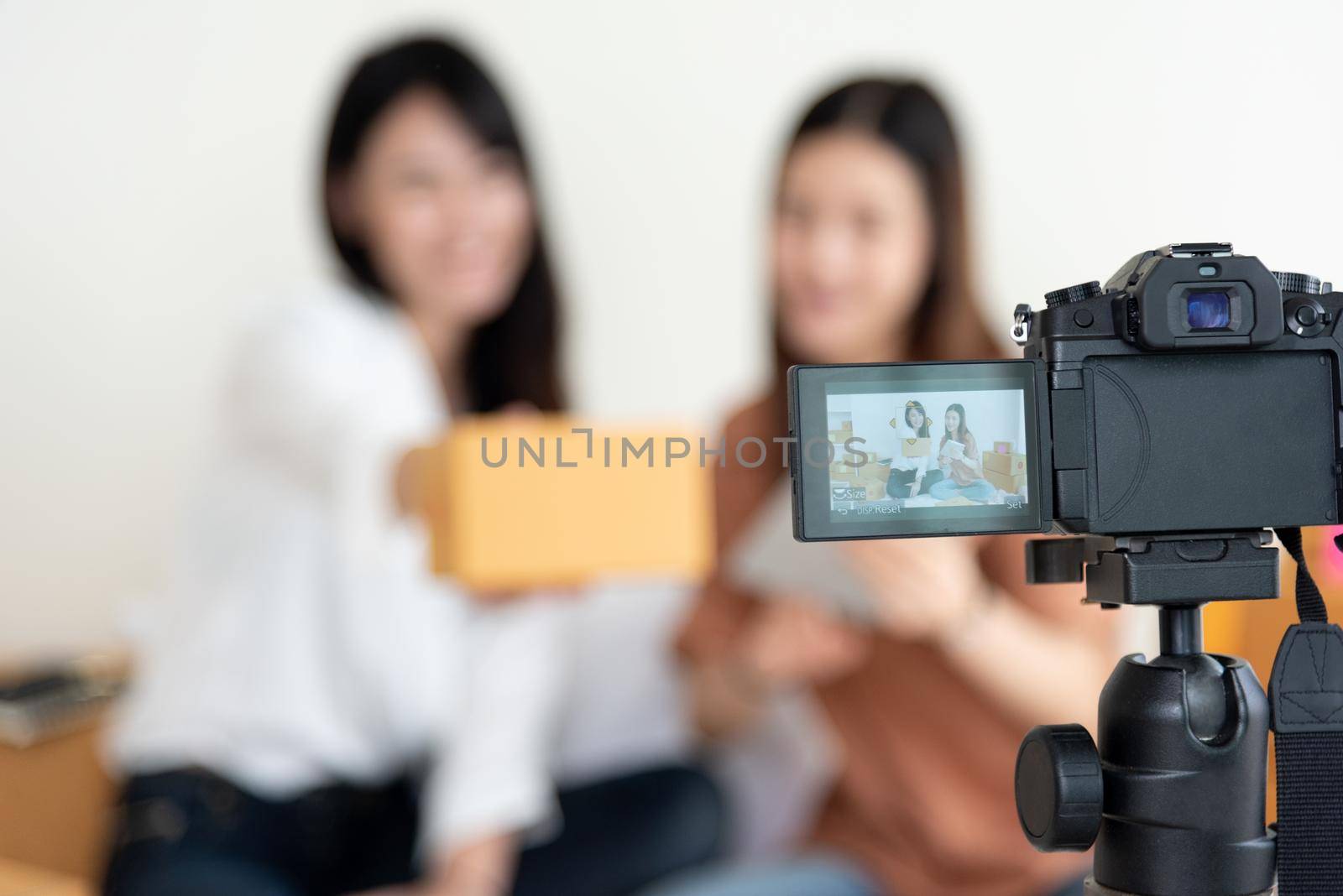 Closeup of digital video camera recording two girls presenting new product advertisement. Vlog and influencer concept. People part time job and occupation. Young teenagers using modern technology by MiniStocker