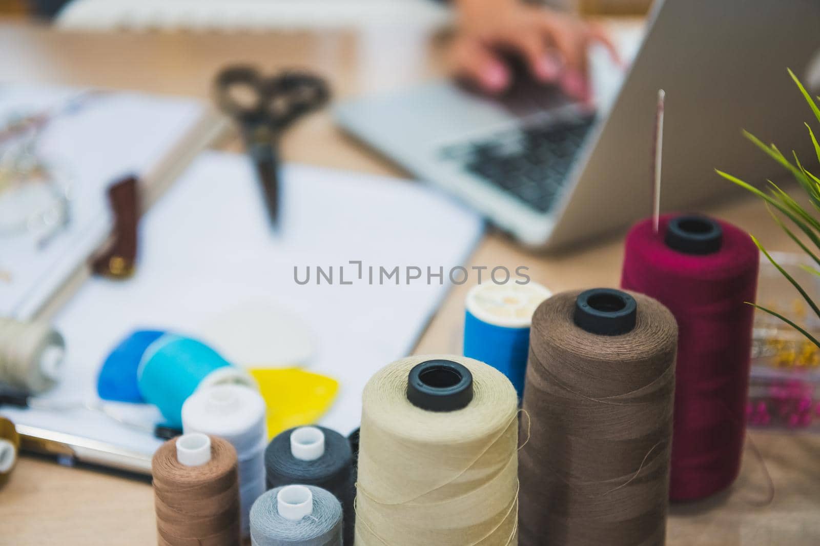Closeup of sewing equipment on fashion designer stylist table. Fashion designer hand working in home office workshop. Stylish fashionista woman creating new cloth design collection. Tailor and sewing