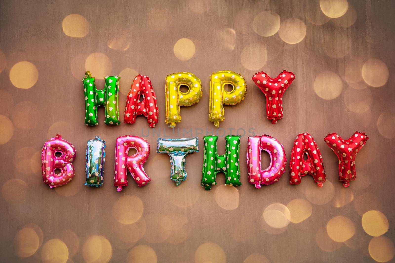 Happy Birthday alphabet text on wall background with golden bokeh defocused light.