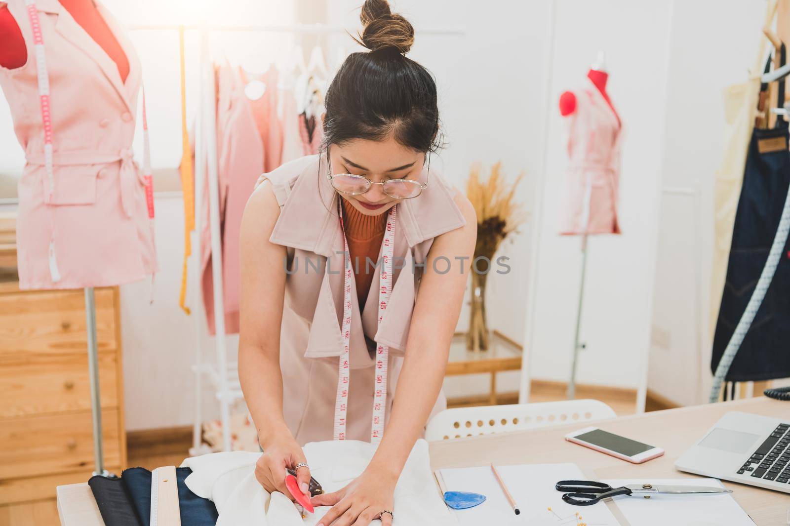 Attractive Asian female fashion designer working in home office workshop. Stylish fashionista woman creating new cloth design collection. Tailor and sewing. People lifestyle and occupation concept