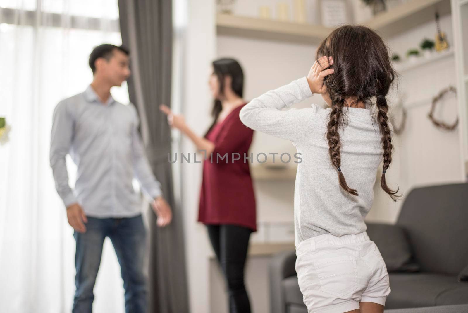 In back view, Little girl puts her hands on her ears because she does not want to hear her dad and mom quarrel. close ears, Family Dramatic scene, Parrents issues, Social and parents problem concept