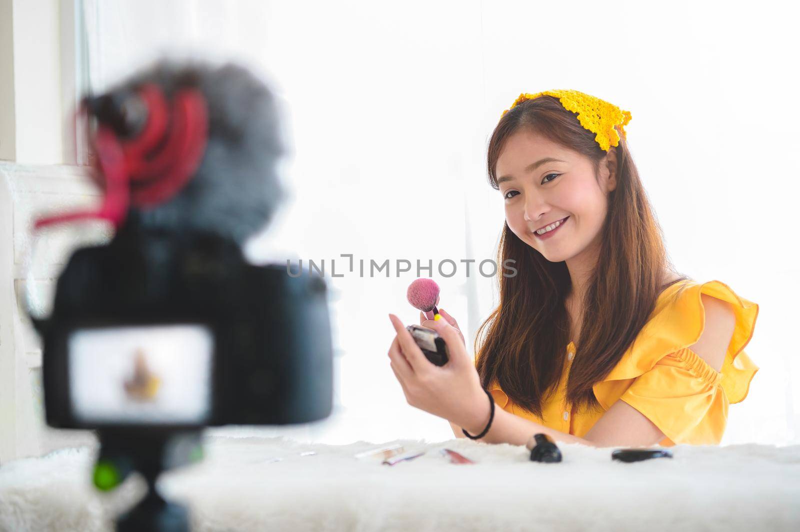 Happy Asian young beauty blogger girl training how to be make up artist in home studio. Woman speaking in front of camera as vlogger. Female vlog blogger recording video tutorial upload to Internet by MiniStocker