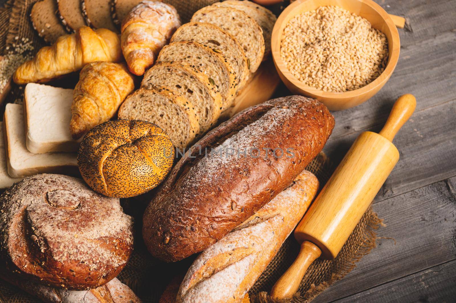 Different kinds of bread with nutrition whole grains on wooden background. Food and bakery in kitchen concept. Delicious breakfast gouemet and meal. Carbohydrate organic food cuisine homemade