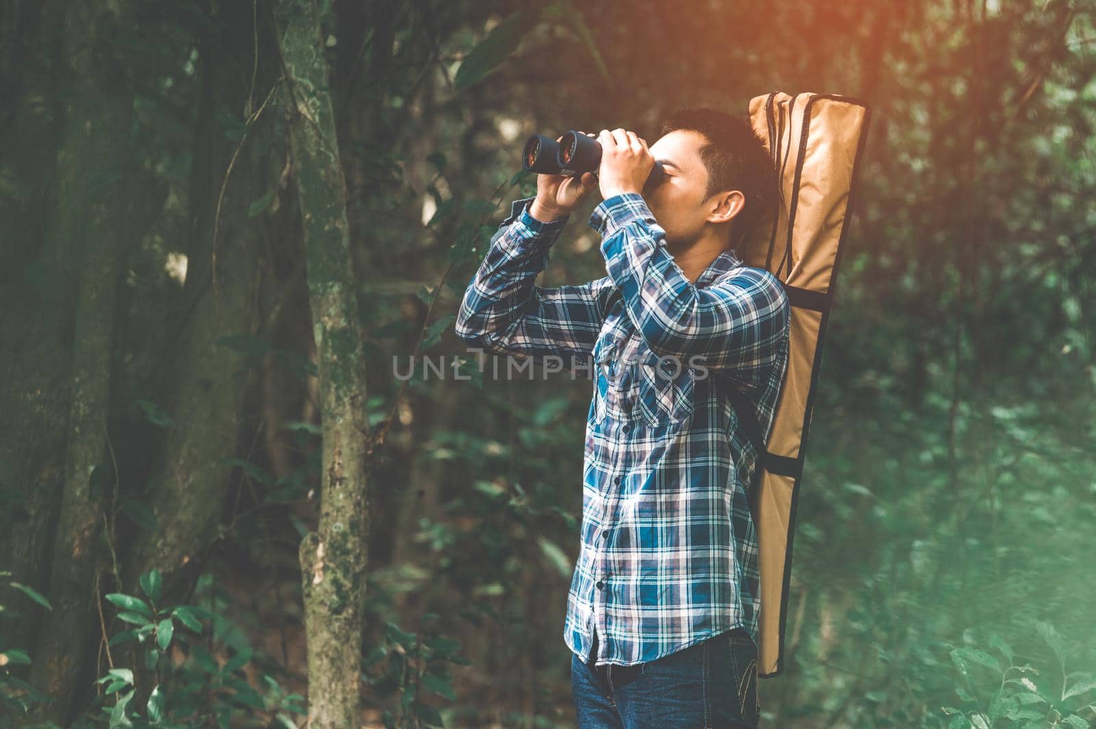 Man with binoculars telescope in forest looking destination as lost people or foreseeable future. People lifestyles and leisure activity concept. Nature and backpacker traveling jungle background
