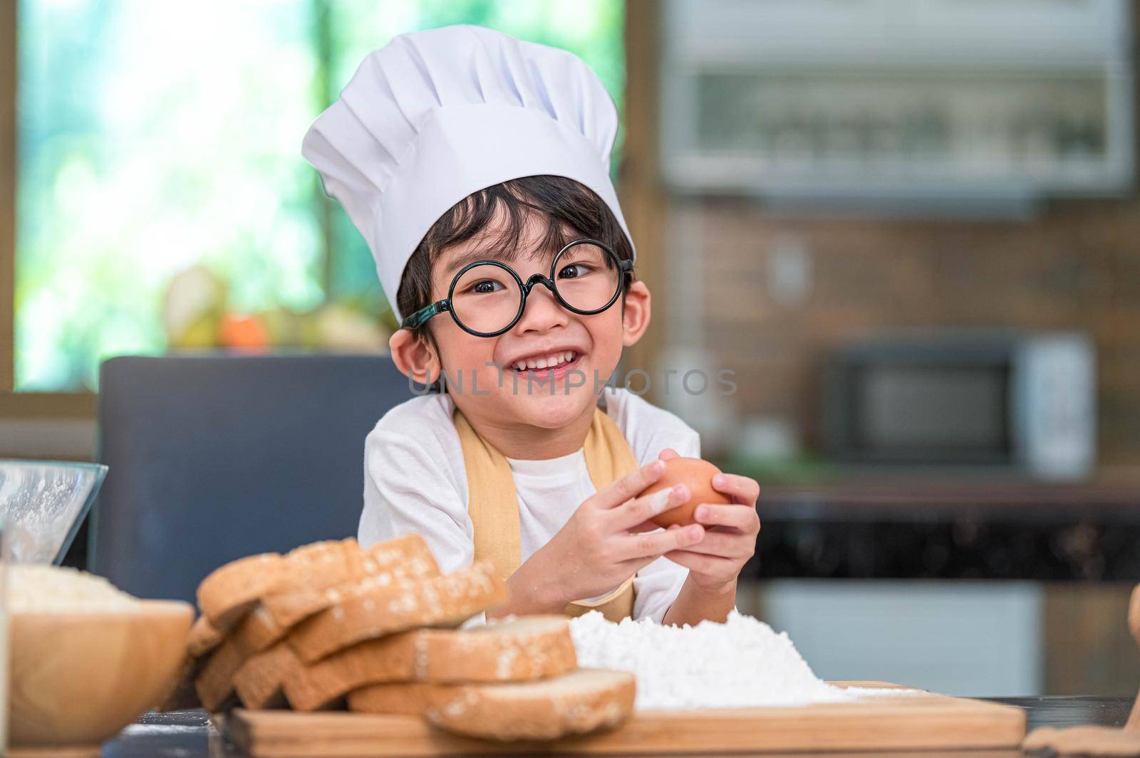 Portrait cute little Asian happiness boy interested in baking bakery with funny in home kitchen. People lifestyles and Family. Homemade food and ingredients concept. Baking Christmas cake and cookies