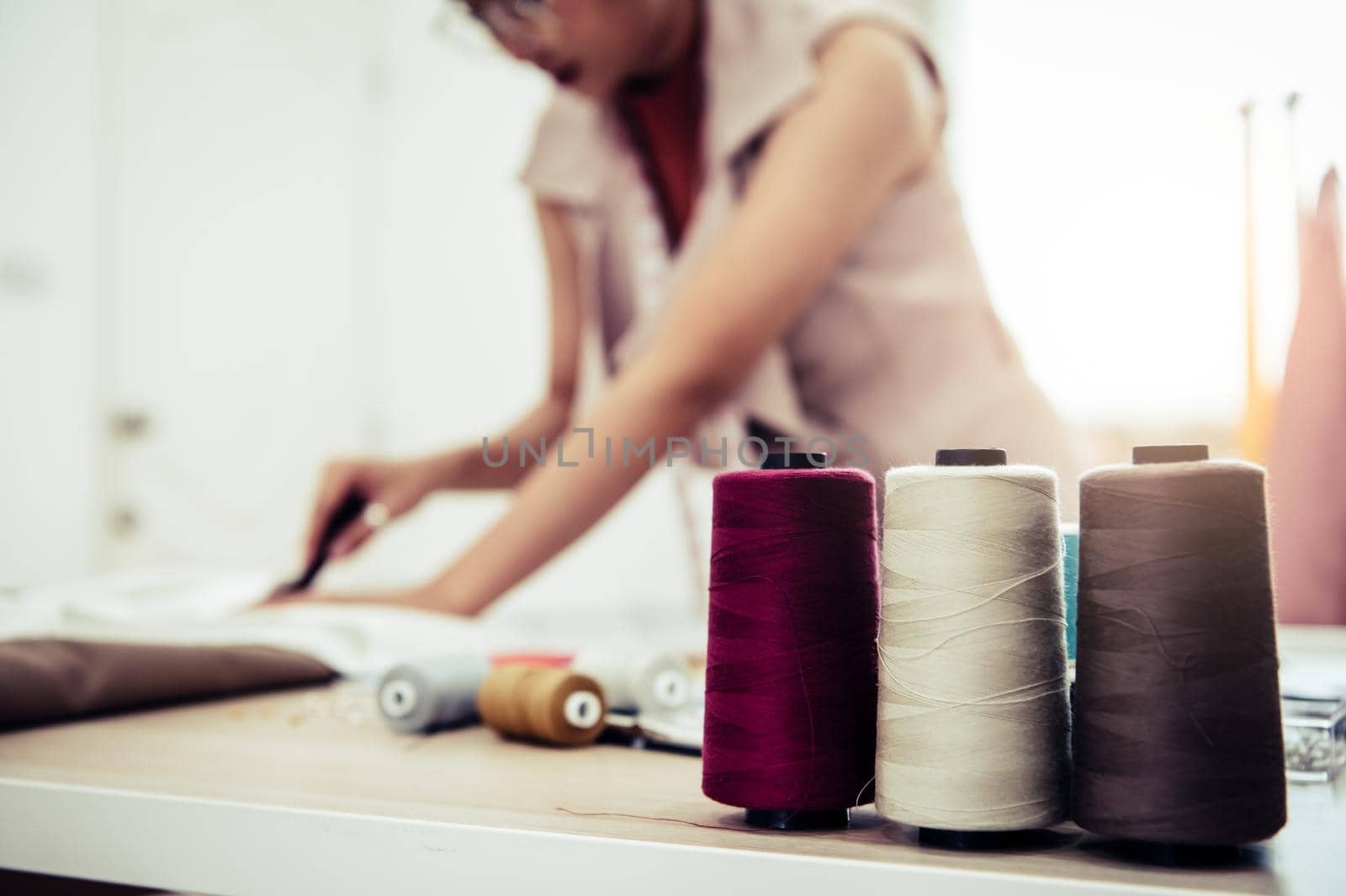 Closeup of colorful thread with fashion designer background in workshop studio. Stylish fashionista woman creating new cloth design collection. Tailoring and sewing People lifestyle and occupation