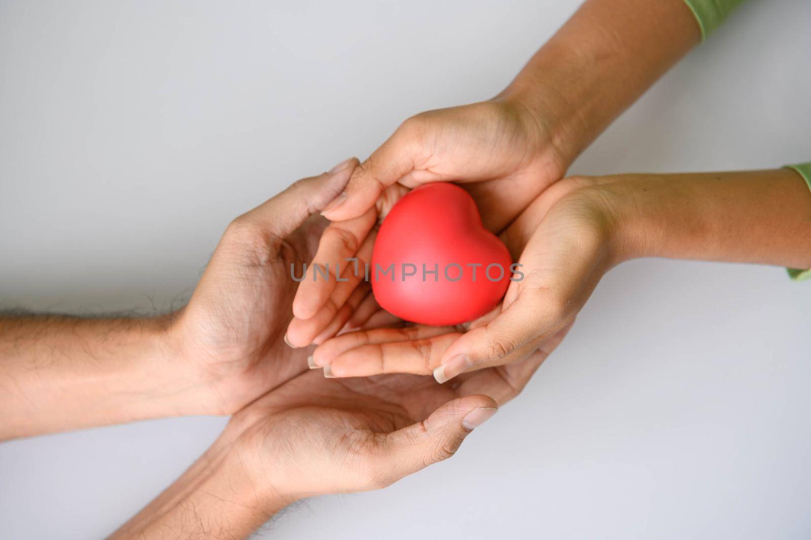 Closeup of Helping hand of heart donor for patient in heart disease. Man give red heart to woman as couple. People lifestyle and couple romance. Healthcare and hospital medical concept