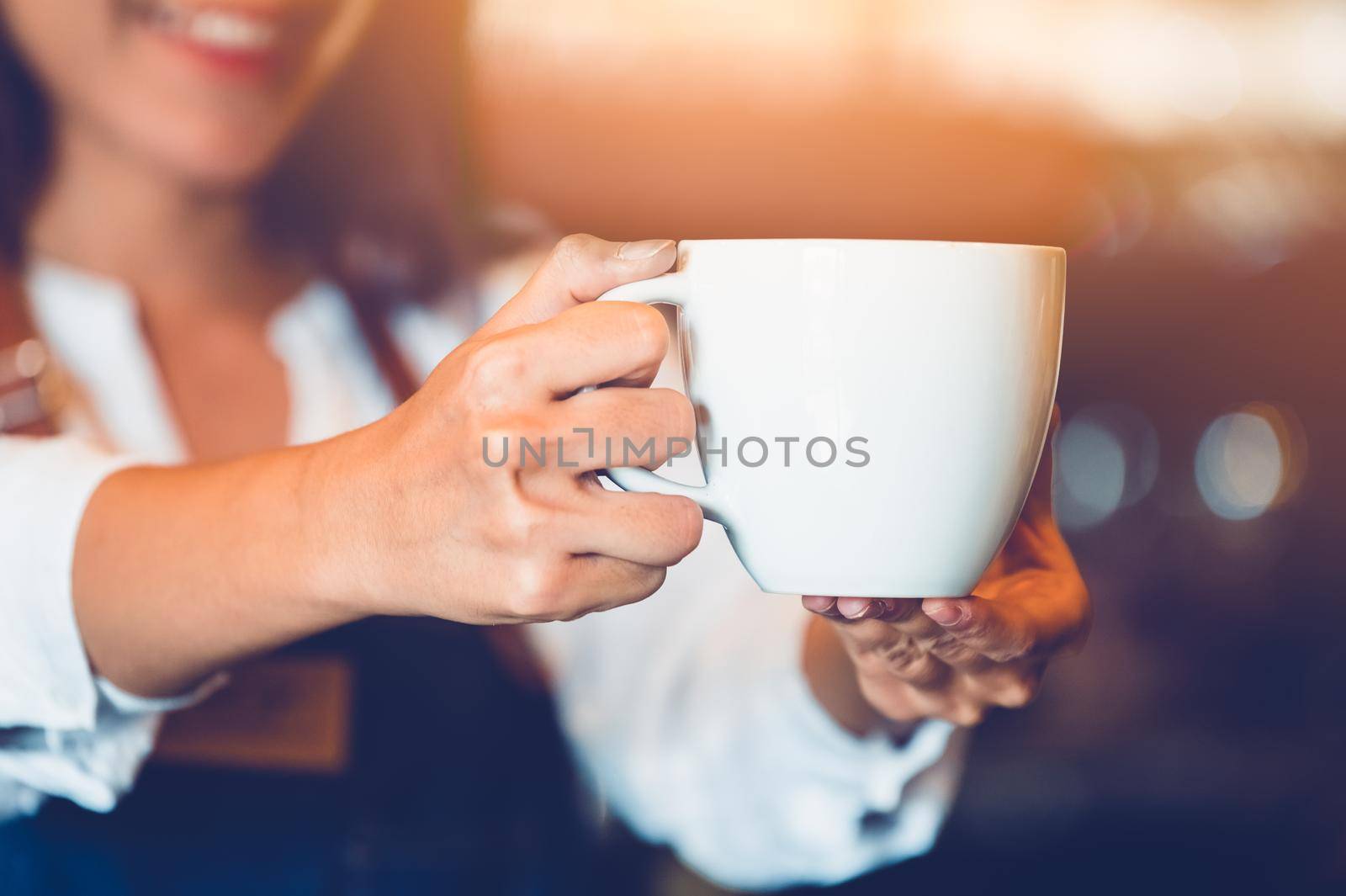 Closeup of professional female barista hand making and holding white cup of coffee. Happy young woman at counter bar in restaurant background. People lifestyles and Business occupation concept