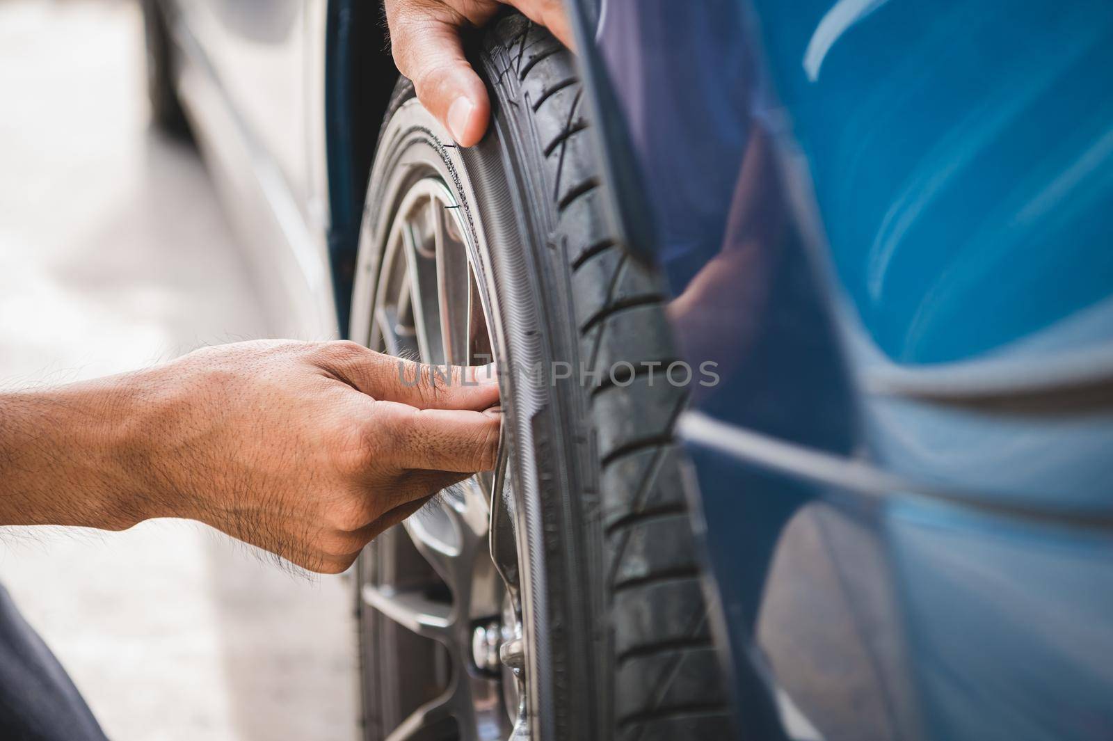 Closeup male automotive technician removing tire valve nitrogen cap for tire inflation service at garage or gas station. Car annual maintenance and repair concept. Safety road trip and travel theme.