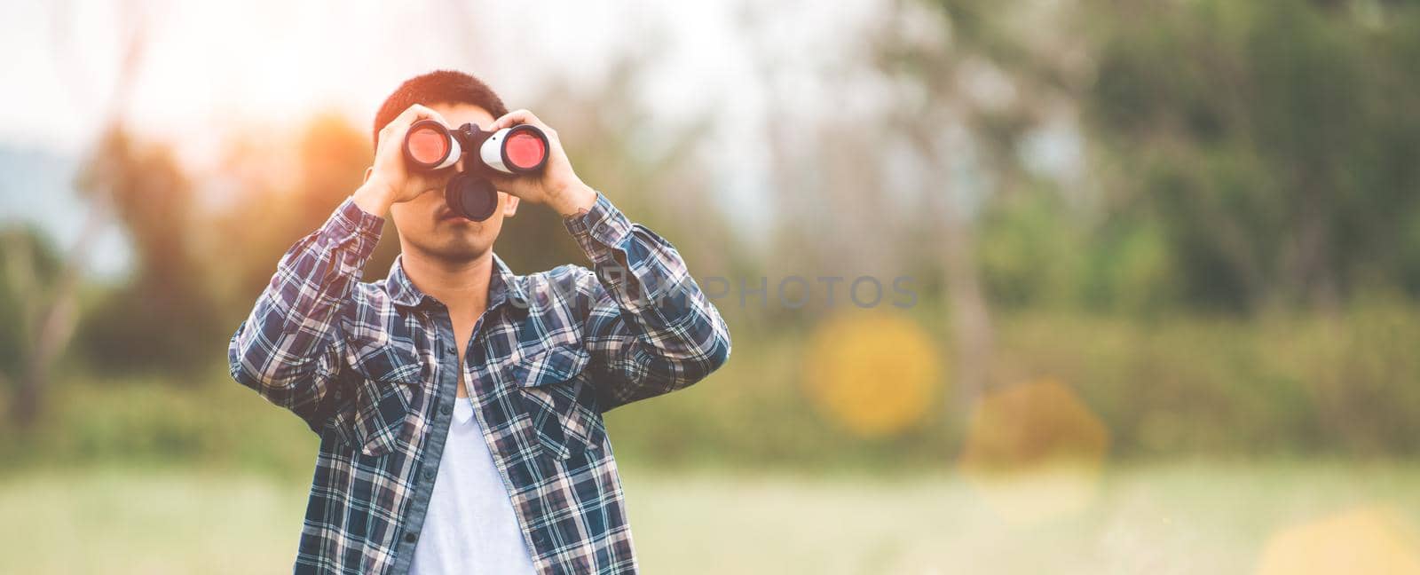 Man with binoculars telescope in forest looking destination as lost people or foreseeable future. People lifestyles and leisure activity concept. Nature and backpacker traveling jungle background by MiniStocker