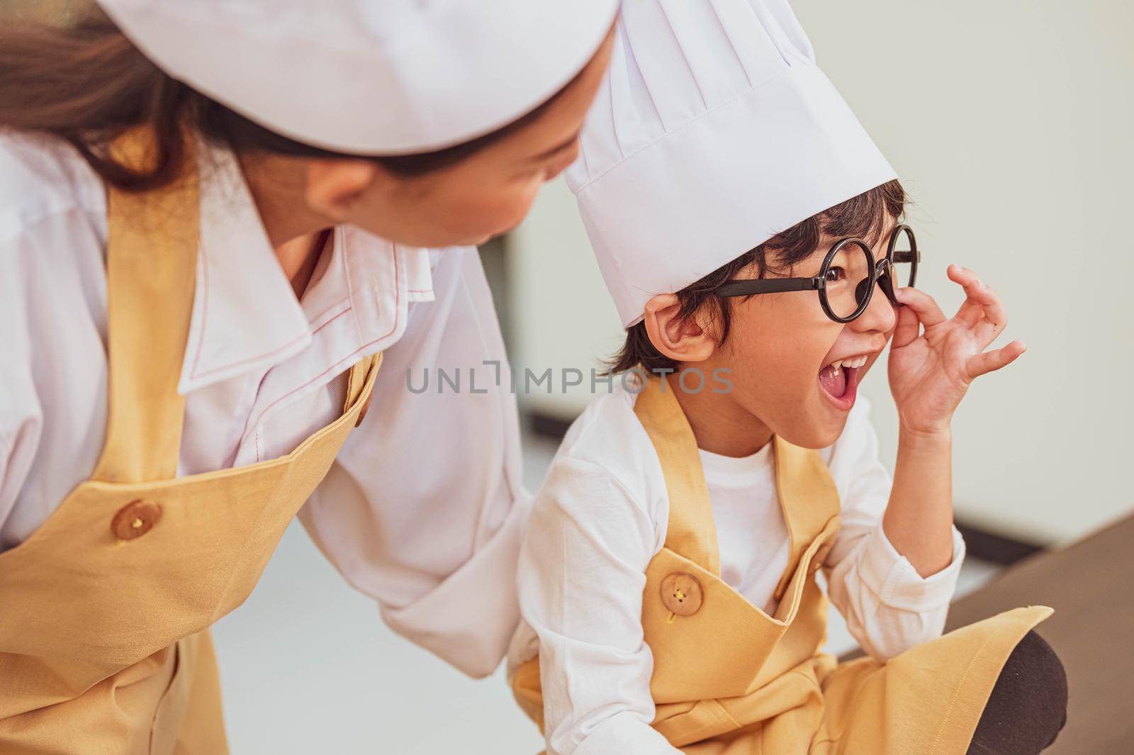 Cute little Asian happy boy interested in cooking with mother funny in home kitchen. People lifestyles and Family. Homemade food and ingredients concept. Two people baking Christmas cake and cookies