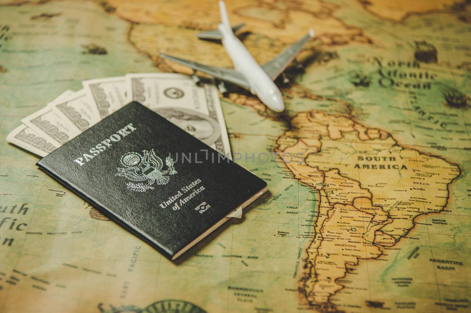 Top view of tourist planning props and travel accessories with American passport, airplane and US dollar banknote money on old grunge style map. Holiday and vacation. Tourism long weekend concept.