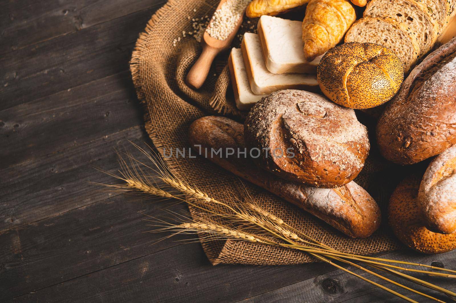 Different kinds of bread with nutrition whole grains on wooden background. Food and bakery in kitchen concept. Delicious breakfast gouemet and meal. Top view angle
