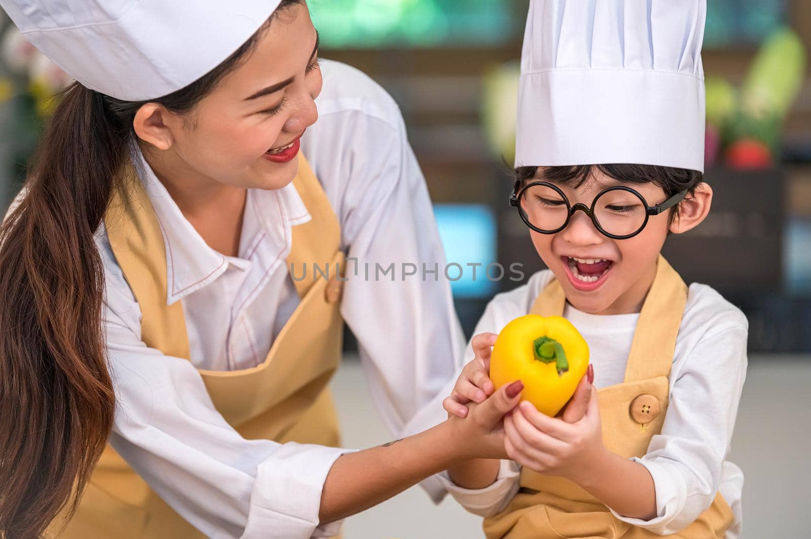 Portrait cute little Asian happy boy chef interested in cooking with mother funny in home kitchen. People lifestyles and Family. Homemade food and ingredient concept. Baking Christmas cake and cookies