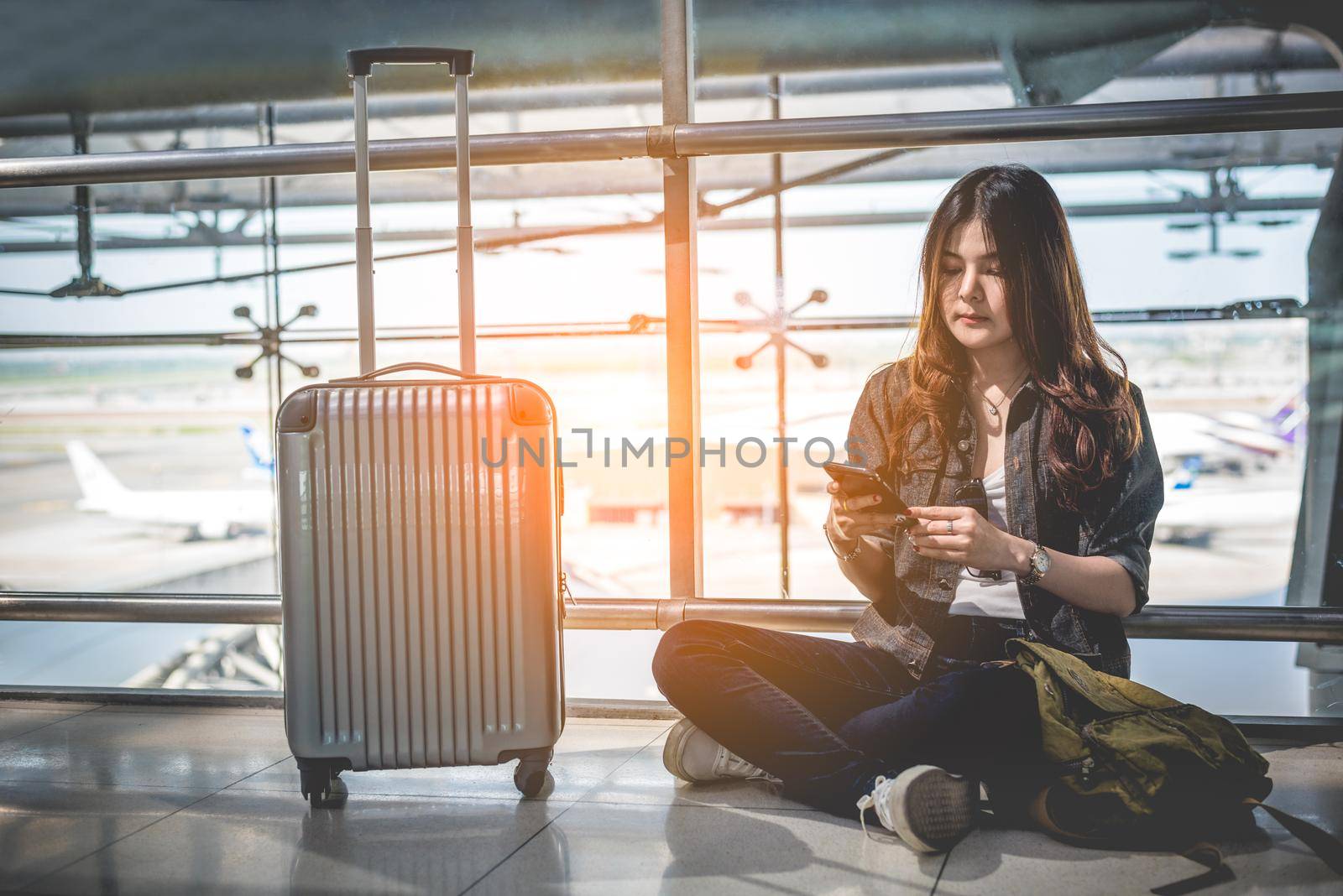 Asian female traveler using smart phone for checking flight time schedule at airport. People and lifestyles concept. Technology and Business concept.