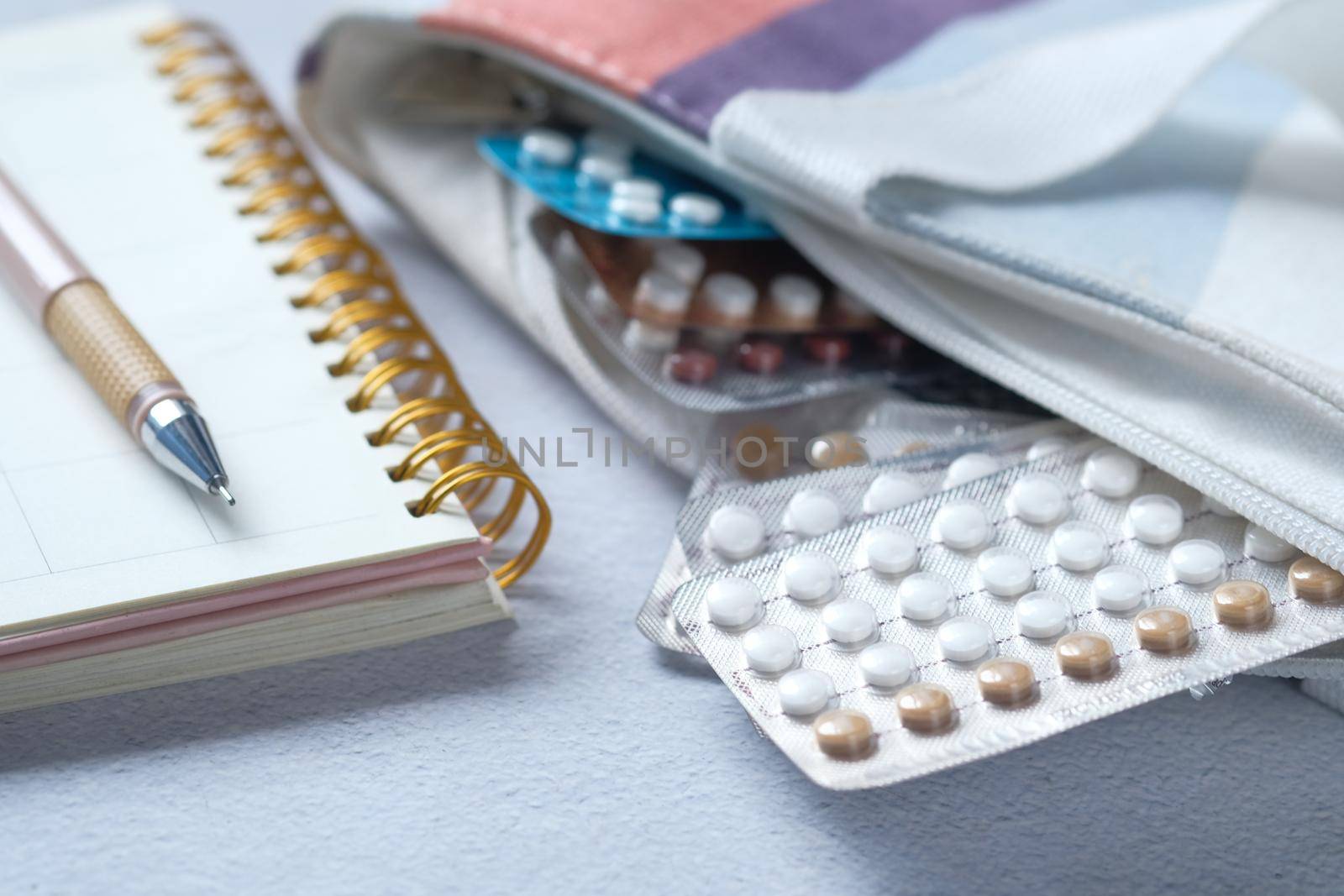 birth control pills in a bag with a planner on table by towfiq007
