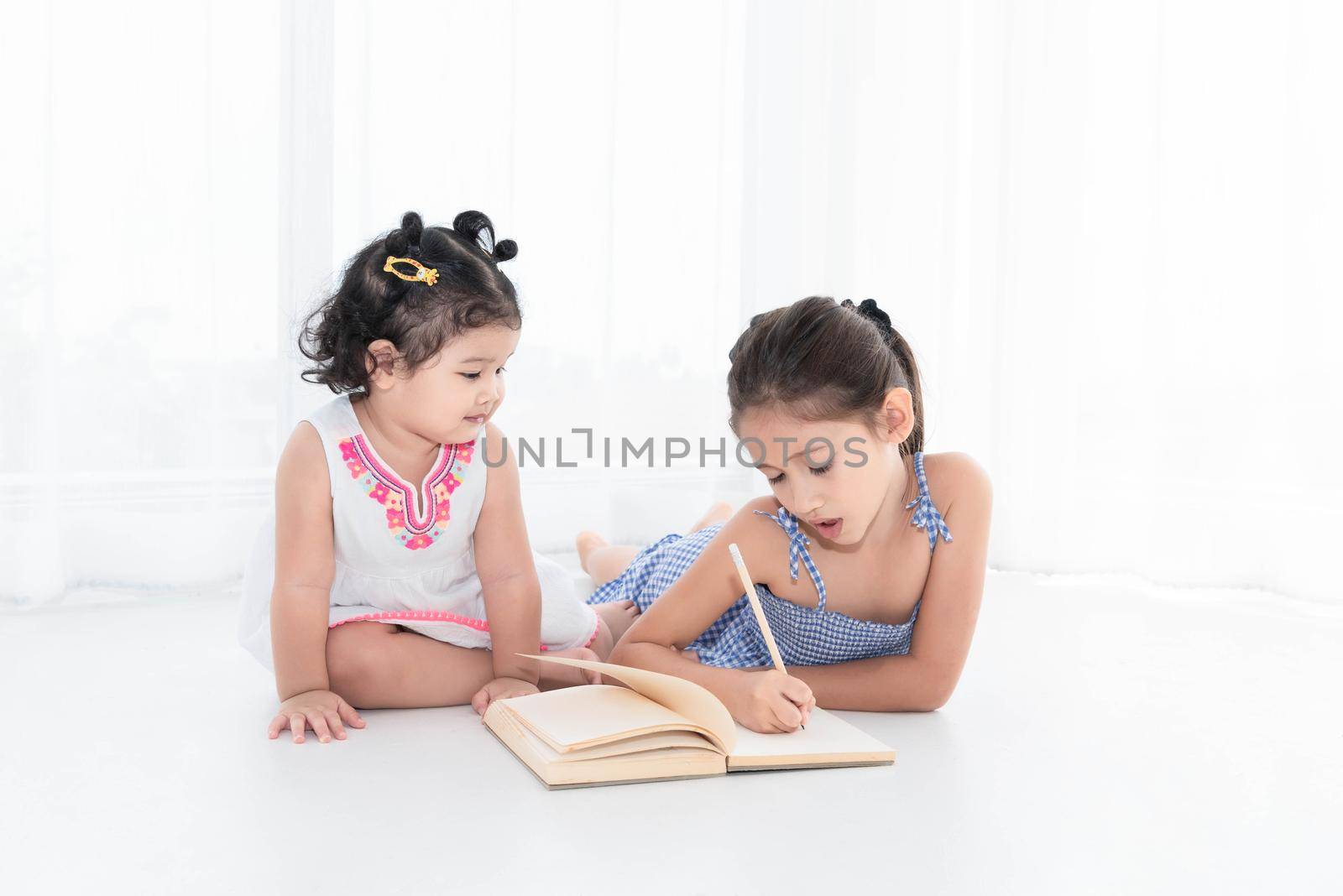 Happy two sister drawing in sketch book together at home or nursery. People lifestyle and kids play. Education and Children concept. Diverse ethnicity and ages. Back to school theme.