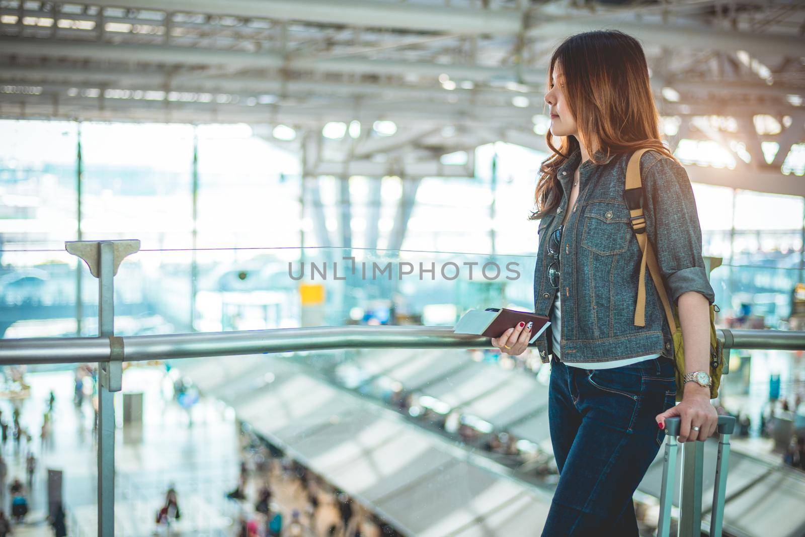 Beauty female tourists holding passport and waiting for flight to take off at airport. People and lifestyles concept. Travel and Adventure theme. Side view portrait.