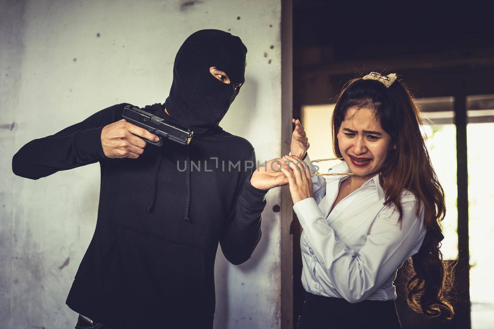 Robber force woman to steal her golden necklace by hand gun in corner of building. Fear of women during facing to thieves. Criminal sexual and illegal violence crisis concept