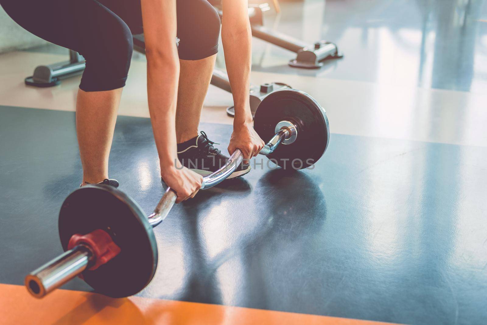 Close up of sports woman lifting weight in fitness gym. Workout exercise and Body build up concept. Barbell lifting and healthy theme.