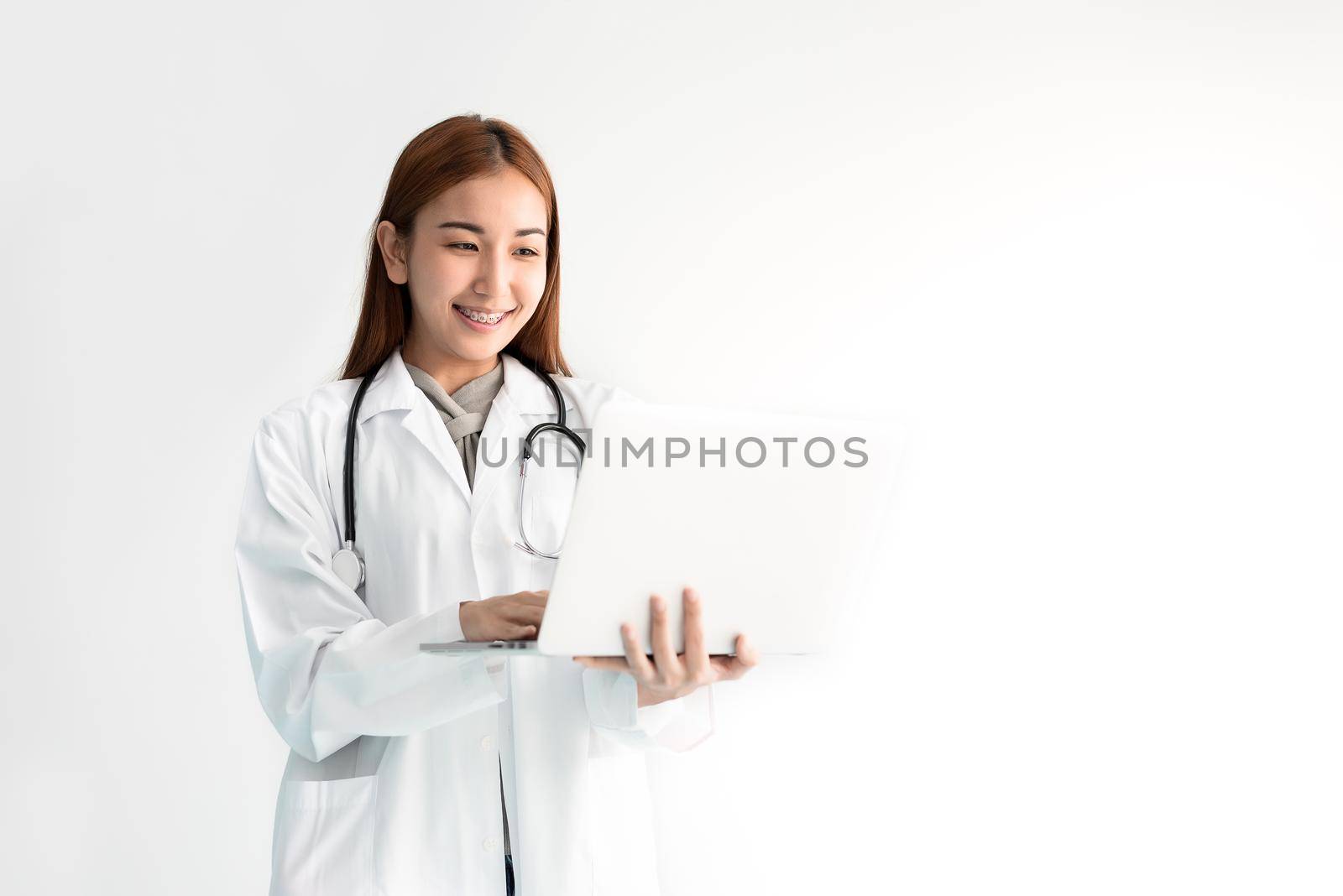 Female doctor using laptop with stethoscope on white background. Medical and Healthcare concept. People and Technology theme by MiniStocker