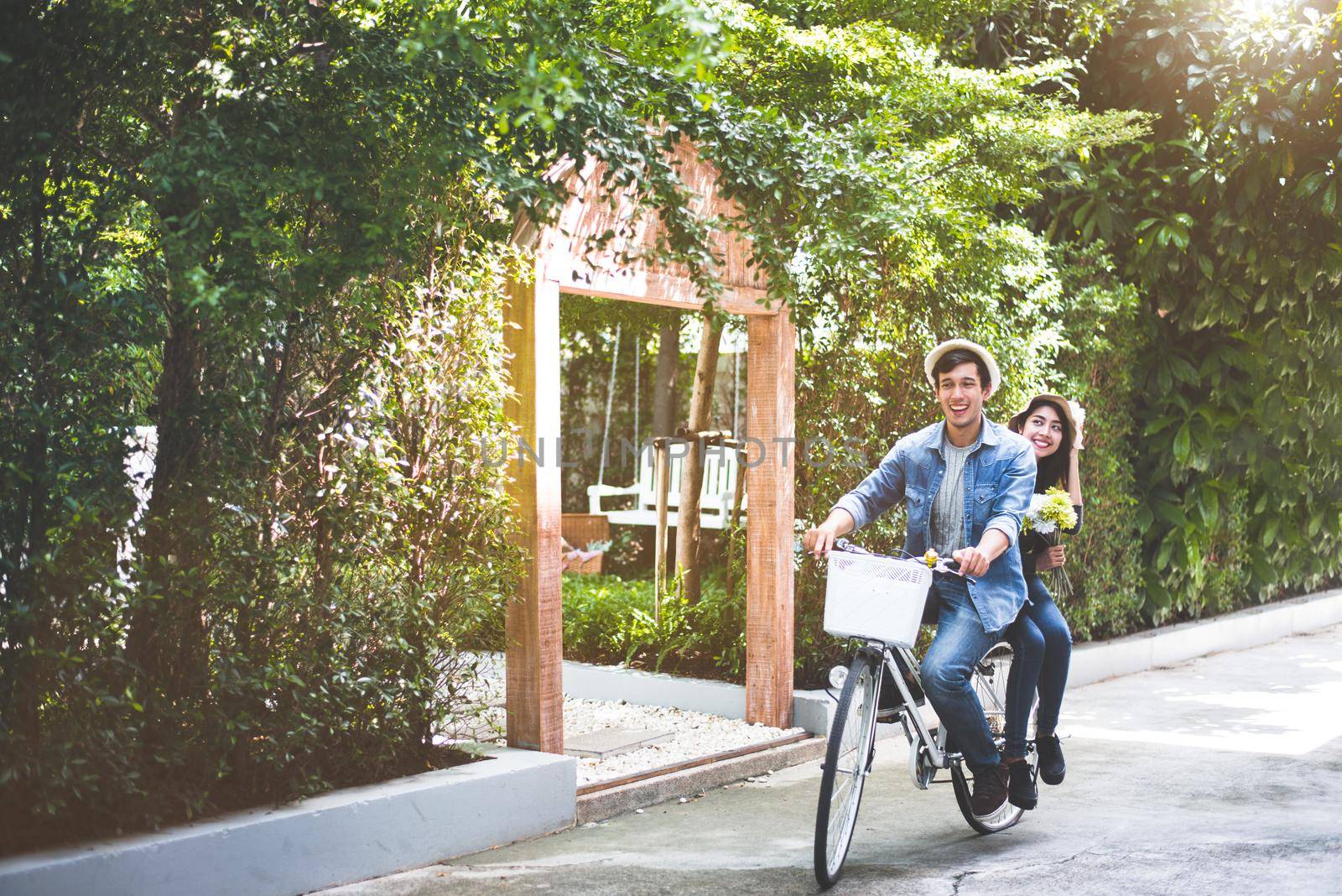 Happy couple riding bicycle together in romantic view park background. Valentine's day and wedding honeymoon concept. People and lifestyles concept.
